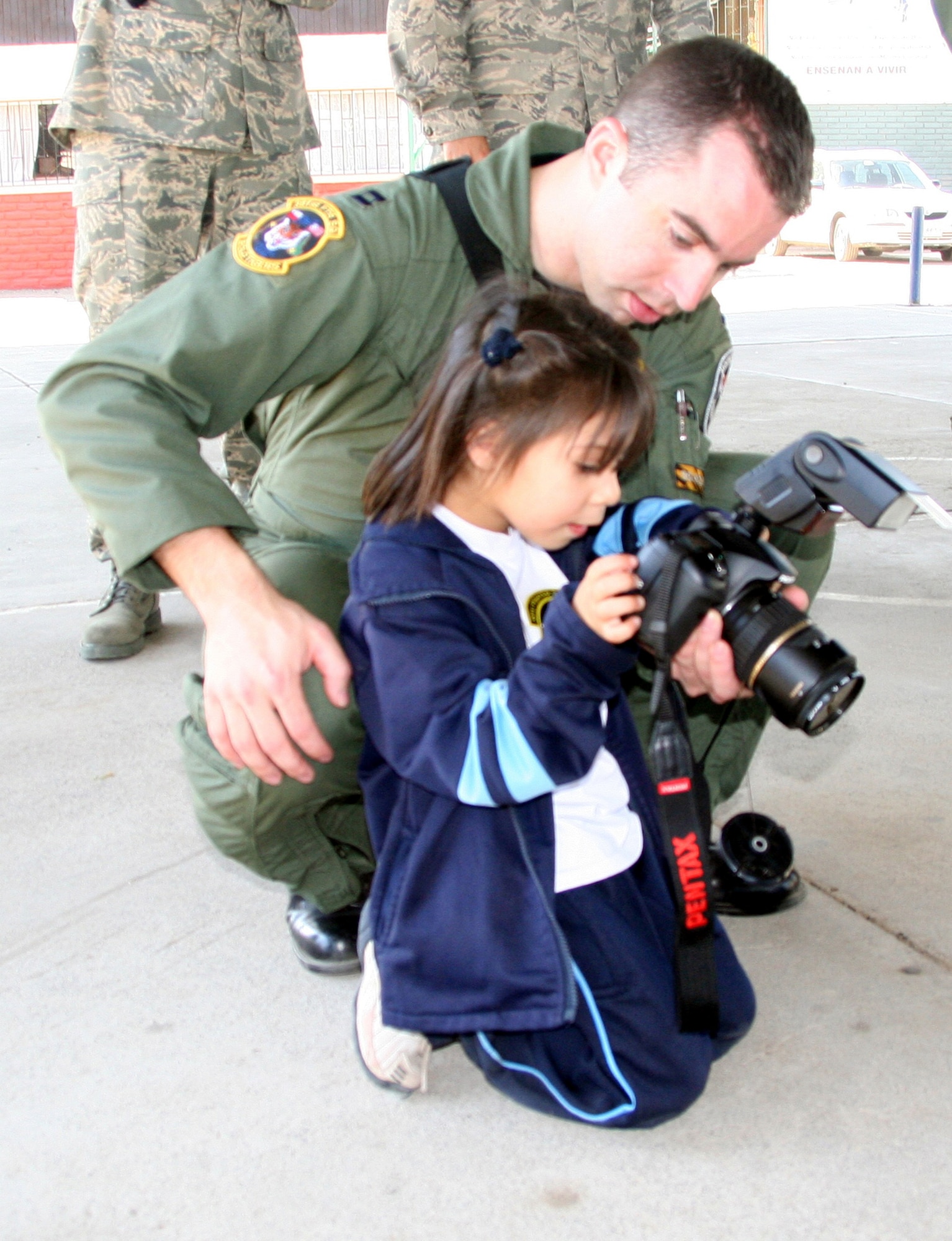 SANTIAGO, Chile - Capt. John Peltier, 391st Fighter Squadron, teaches a Chilean orphan how to take pictures during a performance of the Air Force Band of the Central States at Koinomadelfia Orphanage west of Santiago April 3. Twenty Airmen participating in the FIDAE airshow took a break from aircraft displays and demonstrations to visit more than 30 preschool-aged children at the orphanage to hand out toys, patches and stickers. Koinomadelfia is home to 80 children who have been rescued from domestic violence situations. The FIDAE air show hosts aircraft from 42 countries and is the largest event of its kind in South America. (U.S. Air Force photo by/ 1st Lt. Candace Cutrufo)
