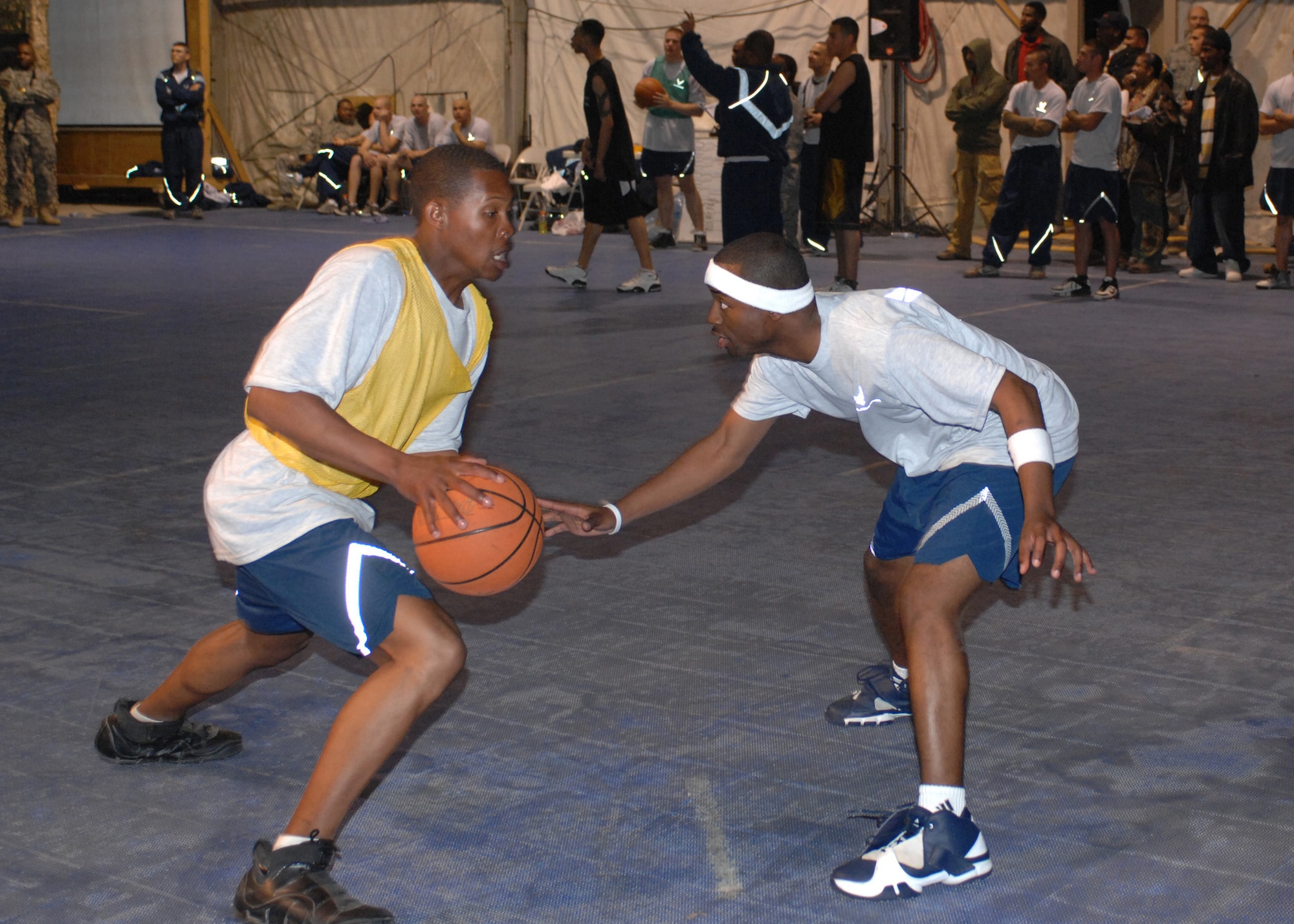 BAGRAM AIR BASE, Afghanistan - Senior Airman Eric Wooten, 455th Expeditionary Security Forces Squadron force protection escort, drives past Staff Sgt. Kevin Clark, 455th Expeditionary Mission Support Squadron services journeyman, in the 3-on-3 March Madness basketball tournament held here April 6. Wooten is deployed from the 81st Communications Squadron, Keesler Air Force Base, Miss., and Clark is deployed from the 919th Services Flight, Eglin Air Force Base, Fla. (U.S. Air Force photo by Master Sgt. Demetrius Lester)