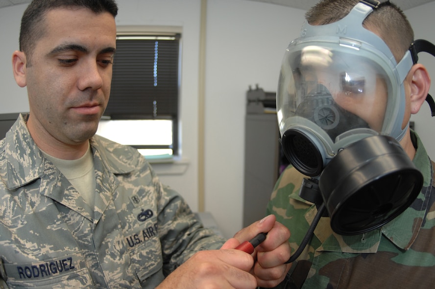 DYESS AIR FORCE BASE, Texas -- Staff Sgt. Andres Rodriguez and Senior Airman Javier Martinez plugs a tube into Airman Martinez's gas mask, April 4. Every Airman must have a fit test on their gas mask before a deployment or chemical warfare training. The tube will measure the amount of particles inside the gas mask and outside, you can only pass if the ratio between the two are at the right levels. (U.S. Air Force photo by Airman 1st Class Jennifer Romig)