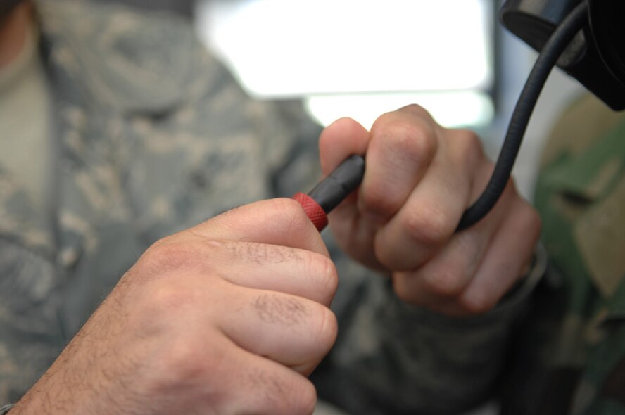 DYESS AIR FORCE BASE, Texas -- Staff Sgt. Andres Rodriguez and Senior Airman Javier Martinez inserts a tube into Airman Martinez's gas mask, April 4. Every Airman must pass a fit test on their gas mask before a deployment. The tube is connected to a machine that will measure the amount of particles inside and outside of the gas mask. An Airman can only pass if the ratio between the two are at the right levels. (U.S. Air Force photo by Airman 1st Class Jennifer Romig)