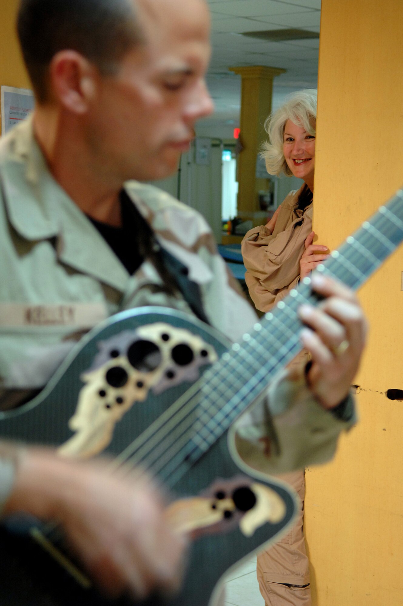 BALAD AIR BASE, Iraq -- Maj. Melinda Screws, 332nd Expeditionary Aeromedical Squadron flight nurse, listens to Tech. Sgt. Jerry Kelley, Hot Brass guitarist, U.S. Air Forces Central Band, performs for an audience at the Contingency Aeromedical Staging Facility hero lounge here, April 8. Three members of Hot Brass performed in various locations throughout the Air Force Theater Hospital to bring smiles and fun to patients and staff. Hot Brass is a part of the U.S. Air Forces Central Band deployed from Scott Air Force Base, Ill. Major Screws is deployed from Patrick Air Force Base, Fla. (U.S. Air Force photo/ Senior Airman Julianne Showalter)