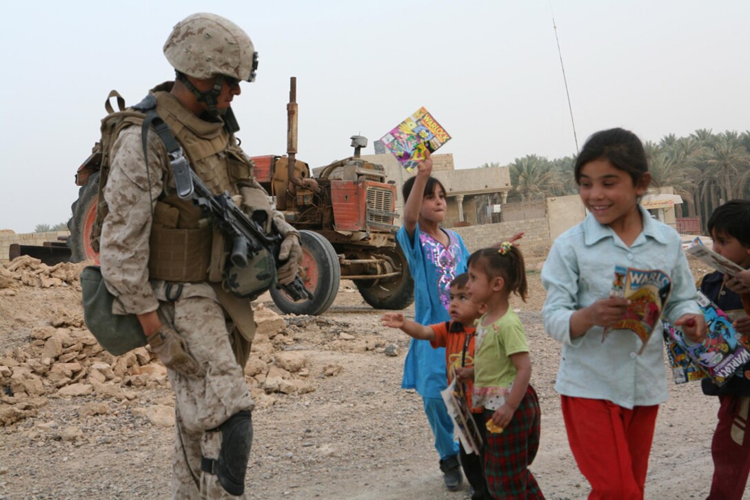 Iraqi children react after Lance Cpl. Miguel F. Alvarez, 20, a rifleman with I Company, 3rd Battalion, 4th Marine Regiment, Regimental Combat Team 5, from La Habra, Calif., hands them comic books at Hit, Iraq, April 10. Marines with I Company have been passing out comics to kids in Hit since they got here in March. Marines say they like handing out comics better then candy because the children can hold on to them longer. ::r::::n:: ::r::::n::