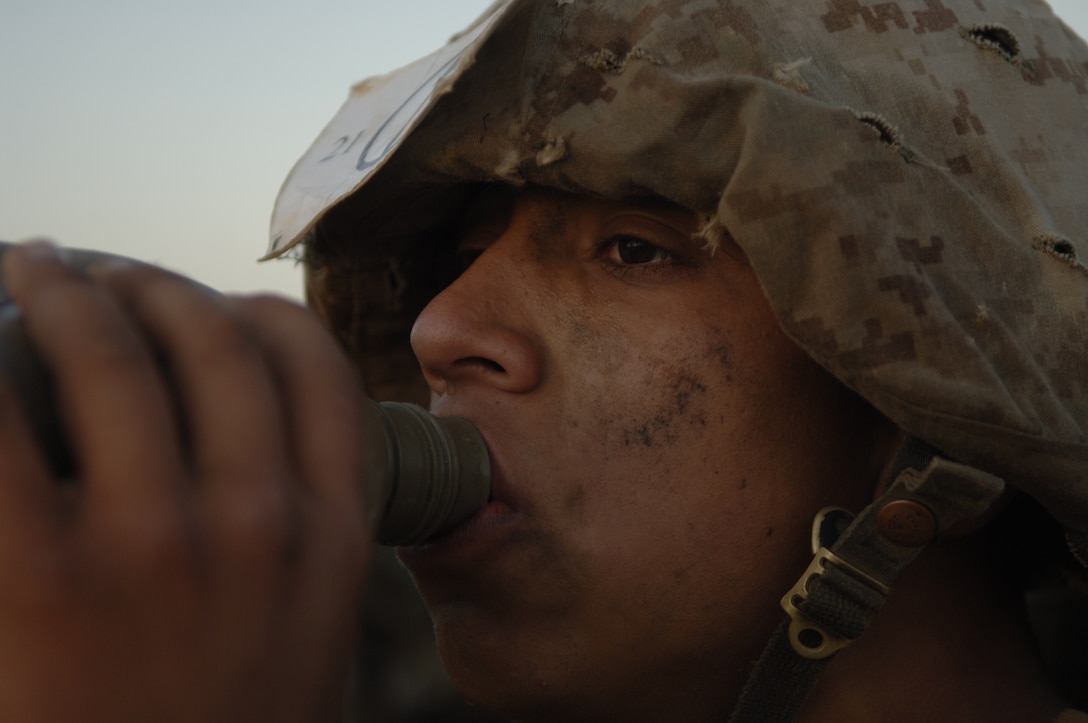 Recruit Eric Pasillas, Platoon 2105, takes a break to drink water from his canteen before finishing the final stretch of the last hike he will do in recruit training. The recruits are encouraged to drink at least 12 canteens of water during the hike. They are given three 10-minute breaks to fill their canteens, adjust their gear and change their socks.