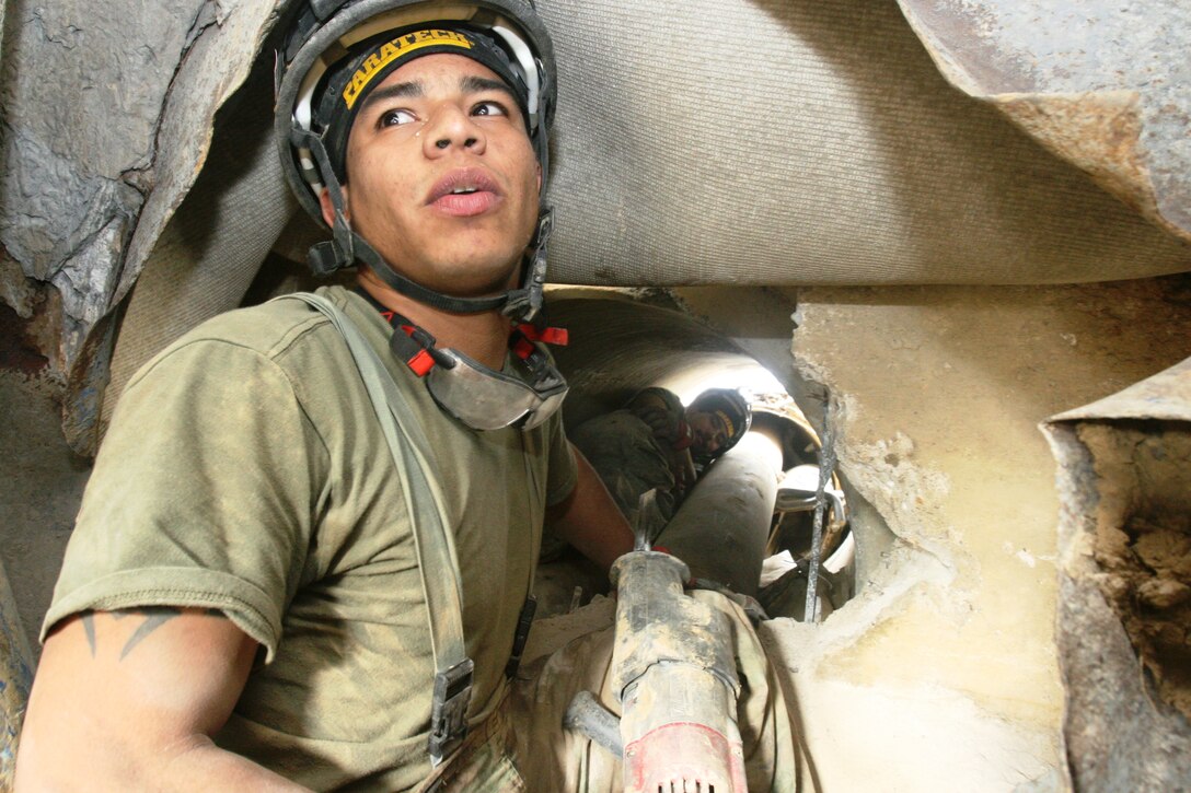 Sgt. Ivan Trevino (front left), technical rescue technician, Technical Rescue Platoon, Headquarters and Service Company, Chemical Biological Incident Response Force, hands a drill to Sgt. Joe L. Martinez (back left), a team leader, to break through a pile of concrete obstructing a path to a simulated casualty. Marines and Navy corpsmen with the Technical Rescue Platoon are able to demonstrate five disciplines, confined space, rope, trench, vehicle extrication, and collapsed structure rescue in personal protective equipment.