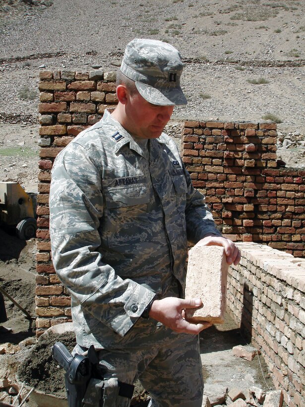 Capt. Jason Aftanas inspects a brick for the wall of a tashnab (bathroom) at the Pukh High School construction site April 1 in Panjshir, Afghanistan. The school will be a two-story, 16-room reinforced concrete structure that will accommodate up to 3,000 students. Captain Aftanas is a Panjshir Provincial Reconstruction Team engineer. Air Force engineers are outside the wire every day conducting site assessments, quality control missions and preparing the province to respond to natural disasters. (U.S. Air Force photo/Capt. Jillian Torango) 