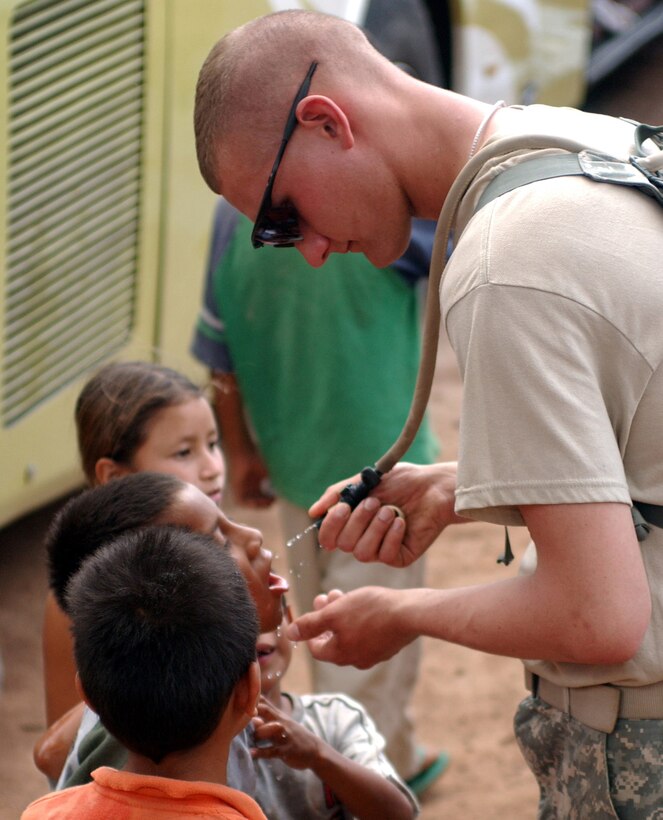 Pfc. Daniel E. Piche of the 1430th Engineer Company from Marquette, Mich., takes some time off from renovating a school in Las Mesas, Honduras, to give local children some water. The 1430th and two other engineer companies are remodeling the school as part of Beyond the Horizon, a mission between the U.S. and Honduran militaries to provide medical services to Honduran citizens and complete construction projects. (Photo by Spc. Andrew A. Reagan, 304th Public Affairs Detatchment.)