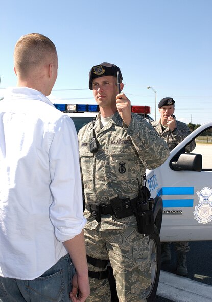 Staff Sgt. Edward Merz, 436th Security Forces Squadron performs a sobriety test while Master Sgt. William Baisey, 436th SFS, radios-in to report the incident, during a staged enactment of stopping a driver suspected of driving under the influence.  (U.S. Air Force photo/Roland Balik)