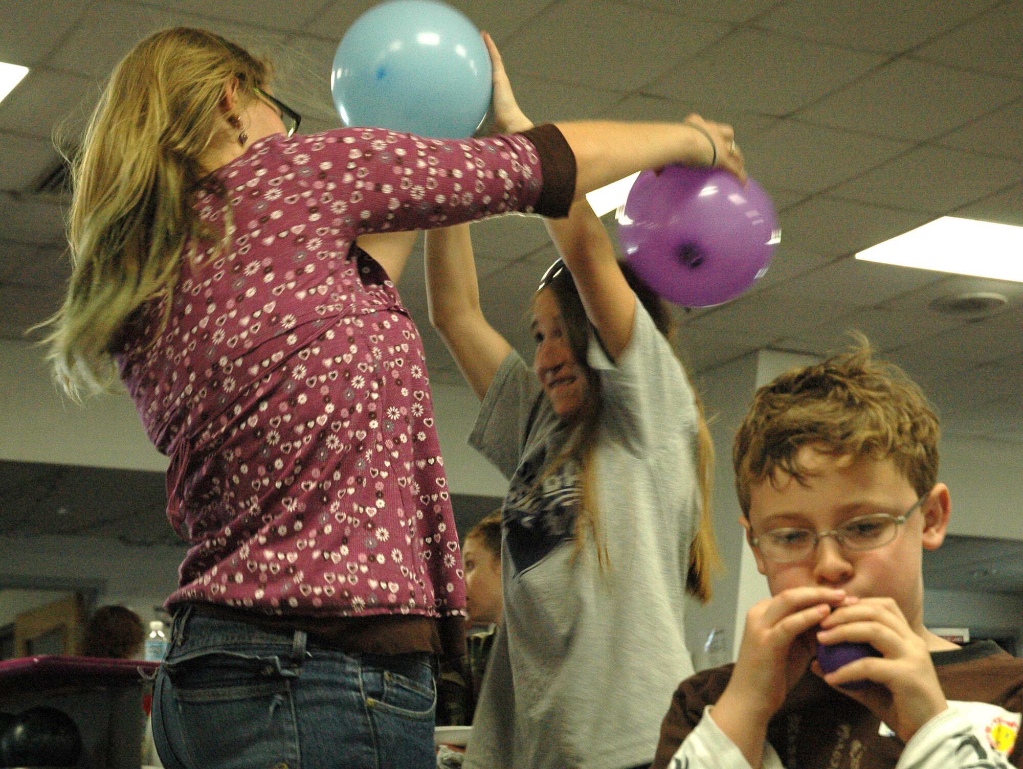 Jenna Hayes, daughter of Lt. Col. John Hayes, 512th Memorial Affairs Squadron commander, and Tasha Cooper, Kent County 4-H program assistant, engage in a balloon fight while Matthew Anderson, son of Capt. Cathy Anderson, 512th Military Personnel Flight commander, prepares more ammunition. Participants of the April 5 "Month of the Military Child" celebration here experienced many events including arts and crafts, a pizza party and a movie presentation.  
