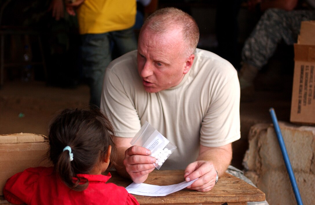 LAGUNA DEL RINCON, Honduras - U.S. Army National Guard Maj. Everett H. Black of C Company, 141st Military Intelligence Battalion, 300th Military Intelligence Brigade of Salt Lake City, Utah, discusses a prescription medication with a child during a visit to this rural town. U.S. military medical personnel are in Honduras for the joint training exercise Beyond the Horizon. The event provides medical attention, as well as infrastructure renovation, to rural areas in this Central American country. (Photo by Sgt. Claude W. Flowers, 304th Public Affairs Detachment.)