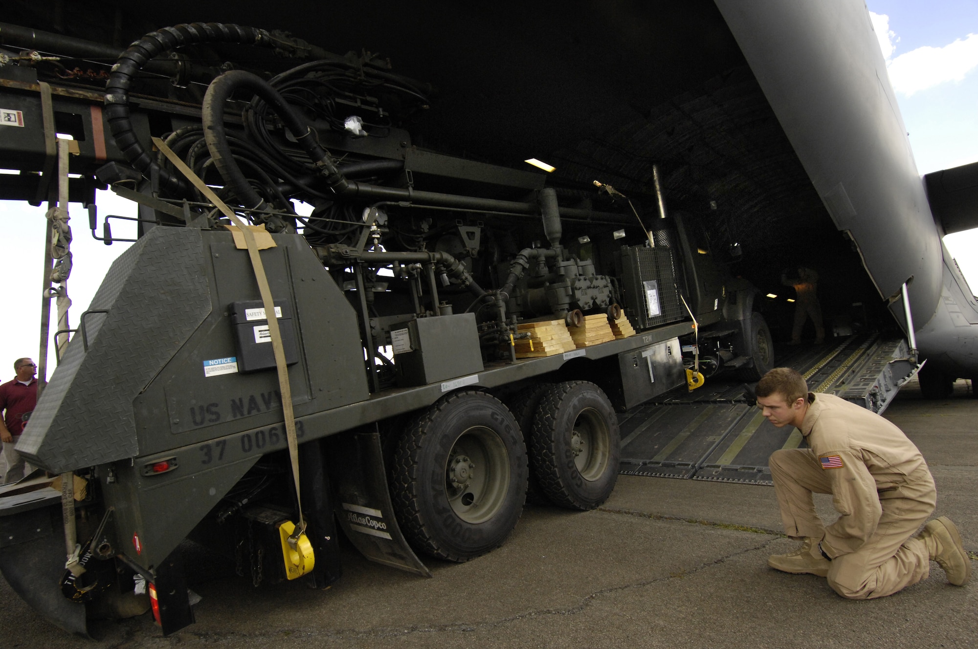 Airman 1st Class Joshua Weston spots while Navy Seabees unload a water-well drilling rig from a C-17 Globemaster III that was transported, along with 20 Navy Seabees, to Nairobi, Kenya from Camp Lemonier, Djibouti in support of a humanitarian well drilling mission enabling critical water supplies to regions in severe drought conditions. Airman Weston is assigned to the 816th Expeditionary Airlift Squadron as a C-17 Loadmaster and is deployed from Charleston Air Force Base, S.C. (U.S. Air Force Photo By: Staff Sgt. Christina M. Styer) 
