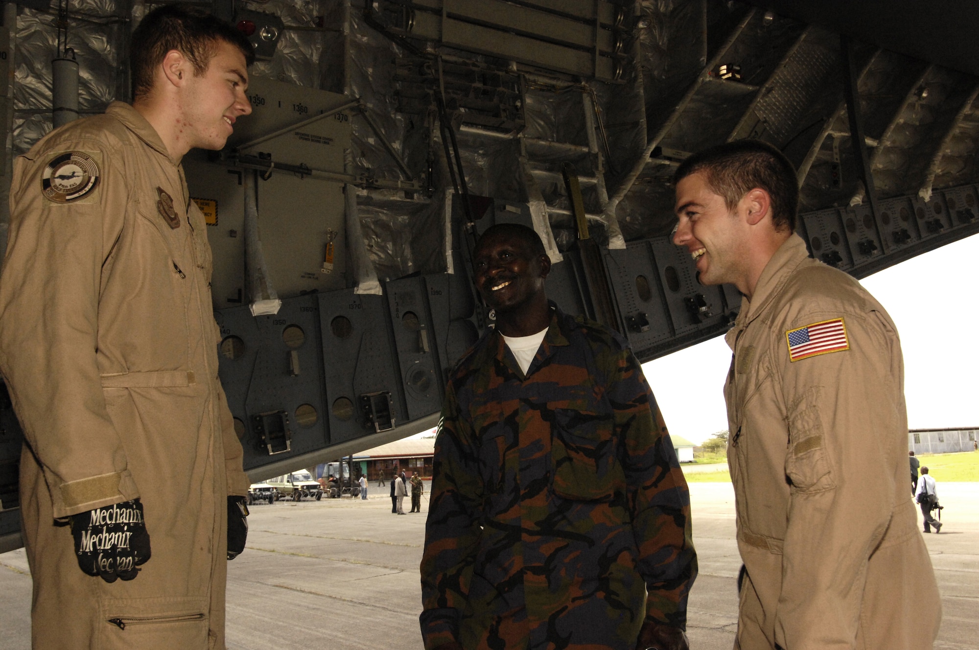 Senior Airman William Graham and Airman 1st Class Joshua Weston speak with Kenyan Army Senior Sgt. Kim Nyota, after transporting and unloading two vehicles and more than 100,000 pounds of water well drilling equipment from a C-17 Globemaster III from Camp Lemonier, Djibouti to Nairobi, Kenya. The C-17 crew also transported 20 Navy Seabees in support of a humanitarian well drilling mission enabling critical water supplies to regions in severe drought conditions. (U.S. Air Force Photo By: Staff Sgt. Christina M. Styer) 