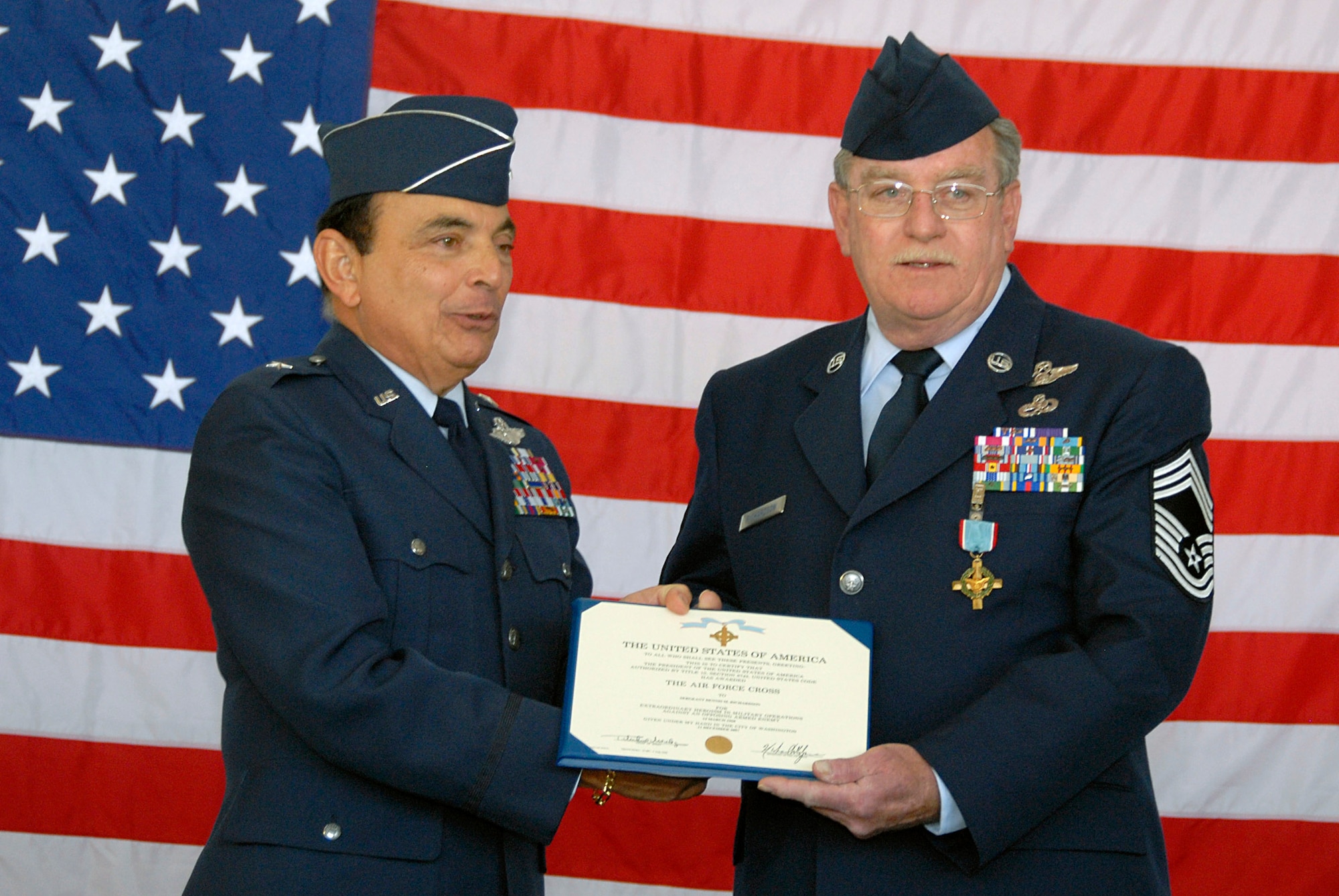 Retired Brig. Gen. Frank Cardile (left) awards retired Chief Master Sgt. Dennis Richardson after presenting him with the Air Force Cross April 5 at the Francis S. Gabreski Airport in New York. Chief Richardson was awarded the Air Force's second-highest honor for valor because of his actions during a March 1968 mission to rescue Airmen in Vietnam. During the mission, Richardson stood exposed in the door of an HH-53 Jolly Green Giant helicopter to fight off enemy forces attempting to board it. (U.S. Air Force photo/Staff Sgt. David J. Murphy) 