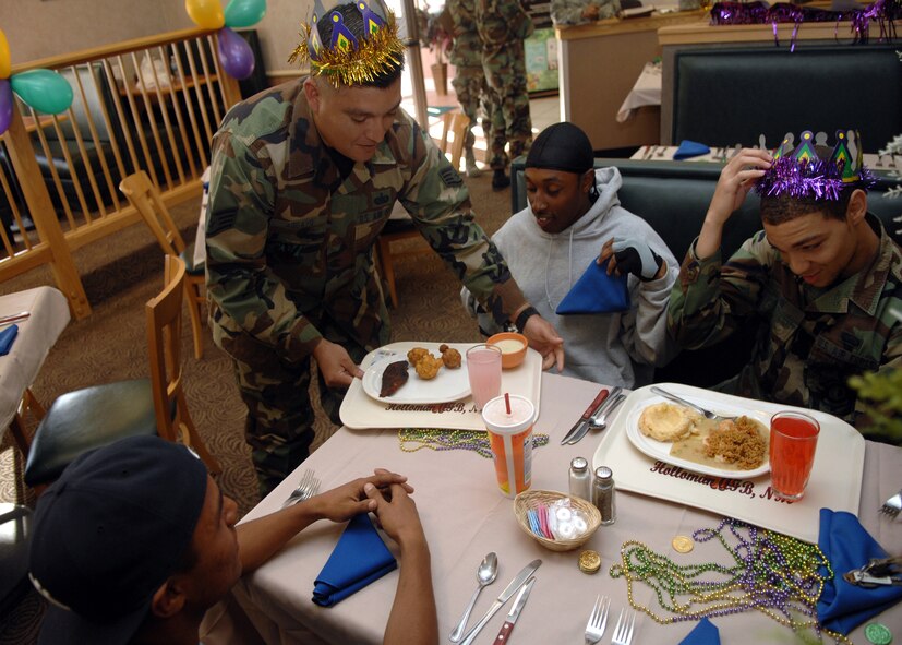 HOLLOMAN AIR FORCE BASE; N.M. -- Airman 1st Class Chad Penn, 49th Maintenance Support Squadron, and Airman 1st Class Devante Bates, 49th Materiel Maintenance Support Squadron, get served their food by Staff Sgt. Jorge Aguayo at the Shifting Sands Dining Facility here March 18. Sergeant Aguayo, a member of the Middle Two, is participating in the quarterly birthday party at the dining facility. The birthday party had a "Mardi Gras" theme this quarter, and any Airmen with a recent birthday who signed up was served dinner by members of the Middle Two. (U.S. Air Force photo by Airman Sondra M. Wieseler)