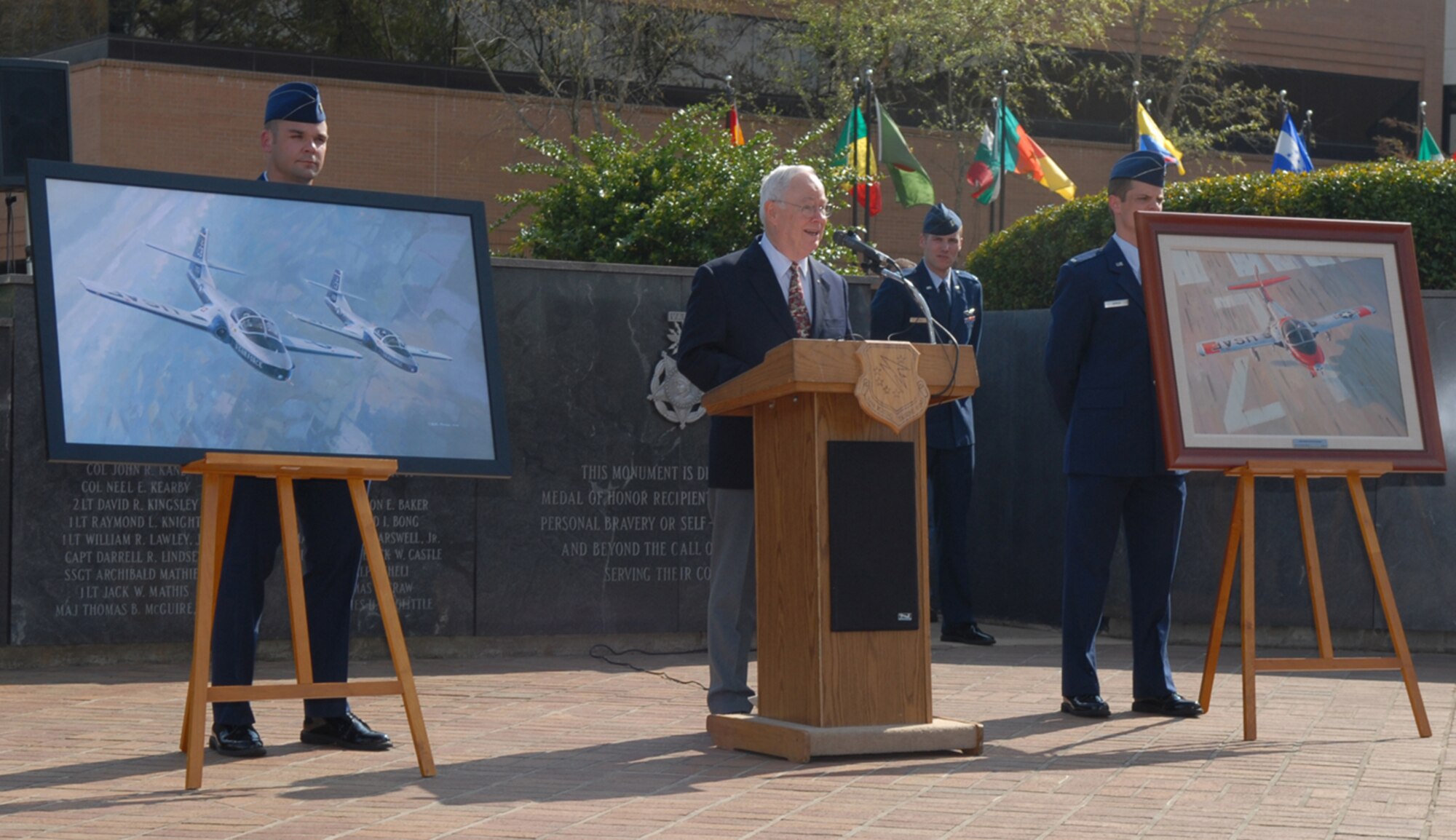 Aviation artist Keith Ferris presents his newest artwork "A Right of Passage" to the 14th Flying Training Wing during the T-37 retirement ceremony April 3. He is also shown with his 1963 original painting "Over the Numbers" on loan here from Air Education and Training Command headquarters for the ceremony. Ferris donated both pieces to the Air Force Art Program. (U.S. Air Force photo by Melissa Duncan)
