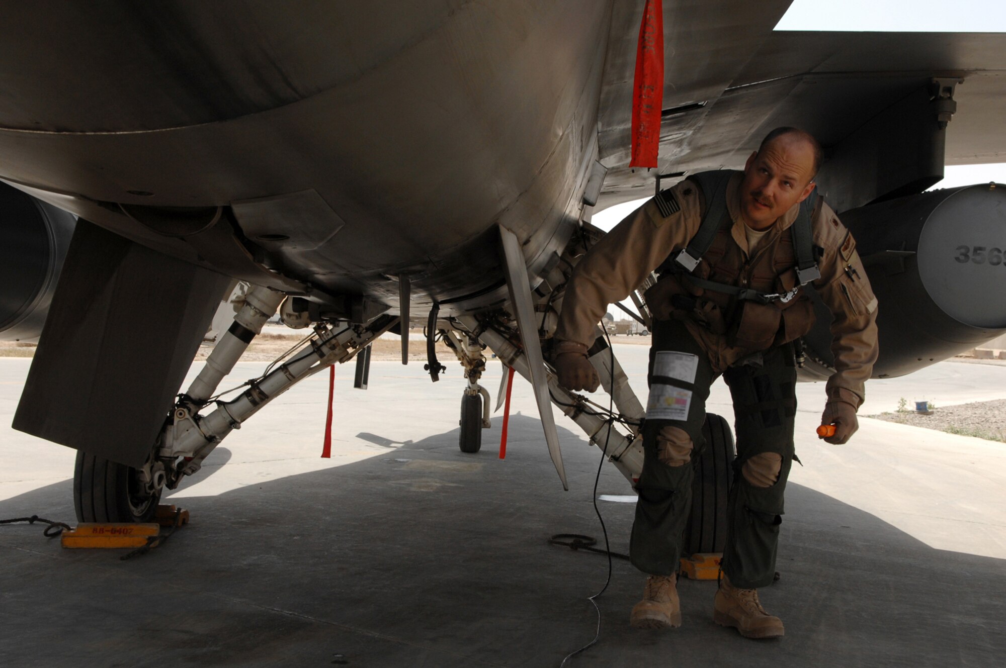 BALAD AIR BASE, Iraq - Maj. Dag Grantham, 332nd Expeditionary Fighter Squadron F-16 pilot, performs a pre-flight inspection on his aircraft prior to a mission here, April 9. Part of the pre-flight inspection includes checking all maintenance panels to make sure they are closed and fuel tank caps are secured. The F-16 Fighting Falcon is a compact, multi-role fighter aircraft, which is highly maneuverable and has proven itself in air-to-air combat and air-to-surface attack. Major Grantham is deployed from Luke Air Force Base, Ariz. (U.S. Air Force photo /Senior Airman Julianne Showalter)