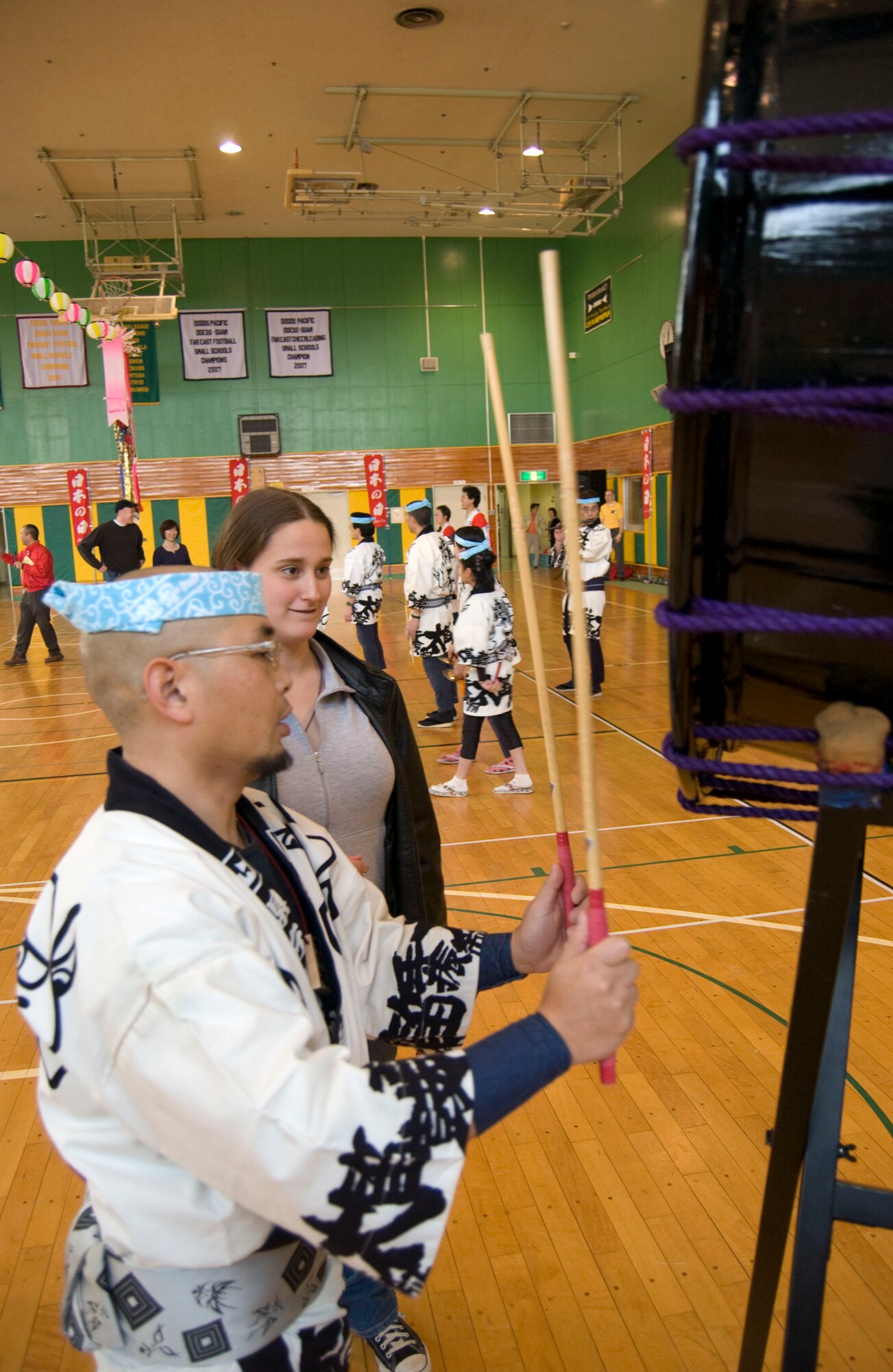 MISAWA AIR BASE, Japan – A member of Aiva teaches Heather Steele how to play the okedo-daiko, a type of Japanese drum, in the Edgren High School gymnasium on April 5, 2008. The Aiva music and dance, part of “Japan Day” at Misawa Air Base, sought to expose Americans to Japanese culture that they wouldn’t have otherwise known about. (U.S. Air Force photo by Senior Airman Samuel Morse)