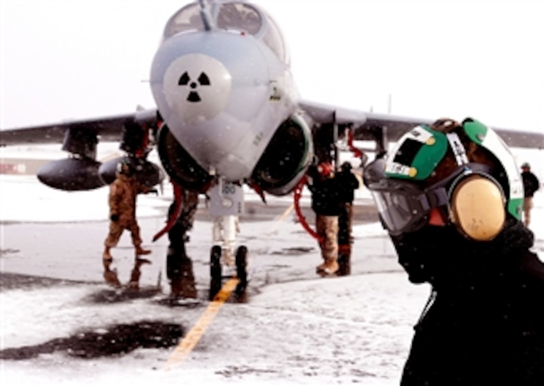 U.S. Navy Petty Officer 2nd Class Wyatt Zarr passes fellow sailors as they perform maintenance on an EA-6B Prowler aircraft on Eielson Air Force Base, Alaska, April 7, 2008. 