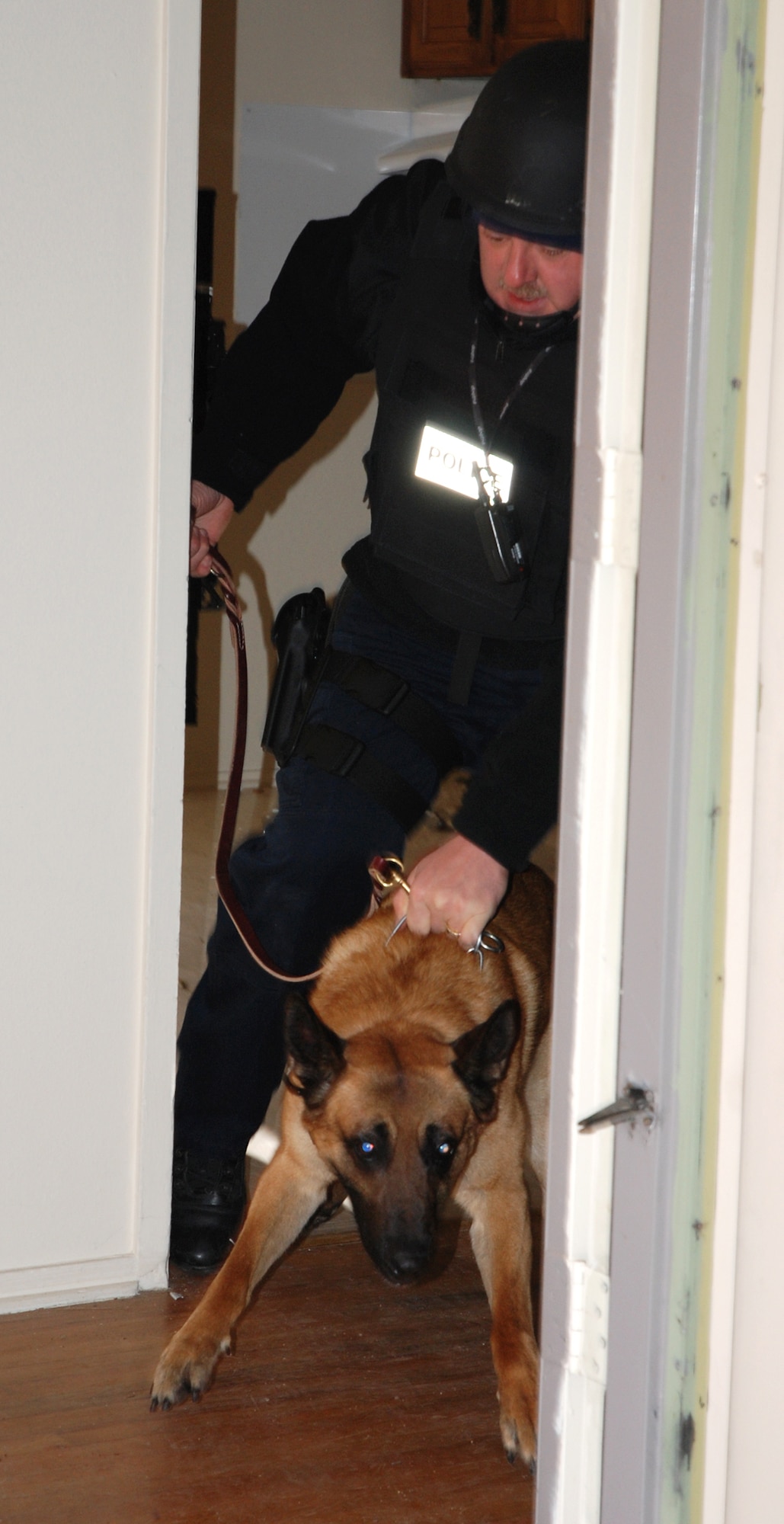 A civilian canine handler restrains his dog after using force to enter a simulated suspect’s house April 11 in the U.S. Air Force Academy base housing complex. Several civilian and military law enforcement agencies around the Colorado Springs area participated in canine Special Weapons and Tactics, or ‘SWAT’ training to better understand the use of dogs during a tactical engagement with criminal or unfriendly forces. (U.S. Air Force photo/Senior Airman Stephen Collier