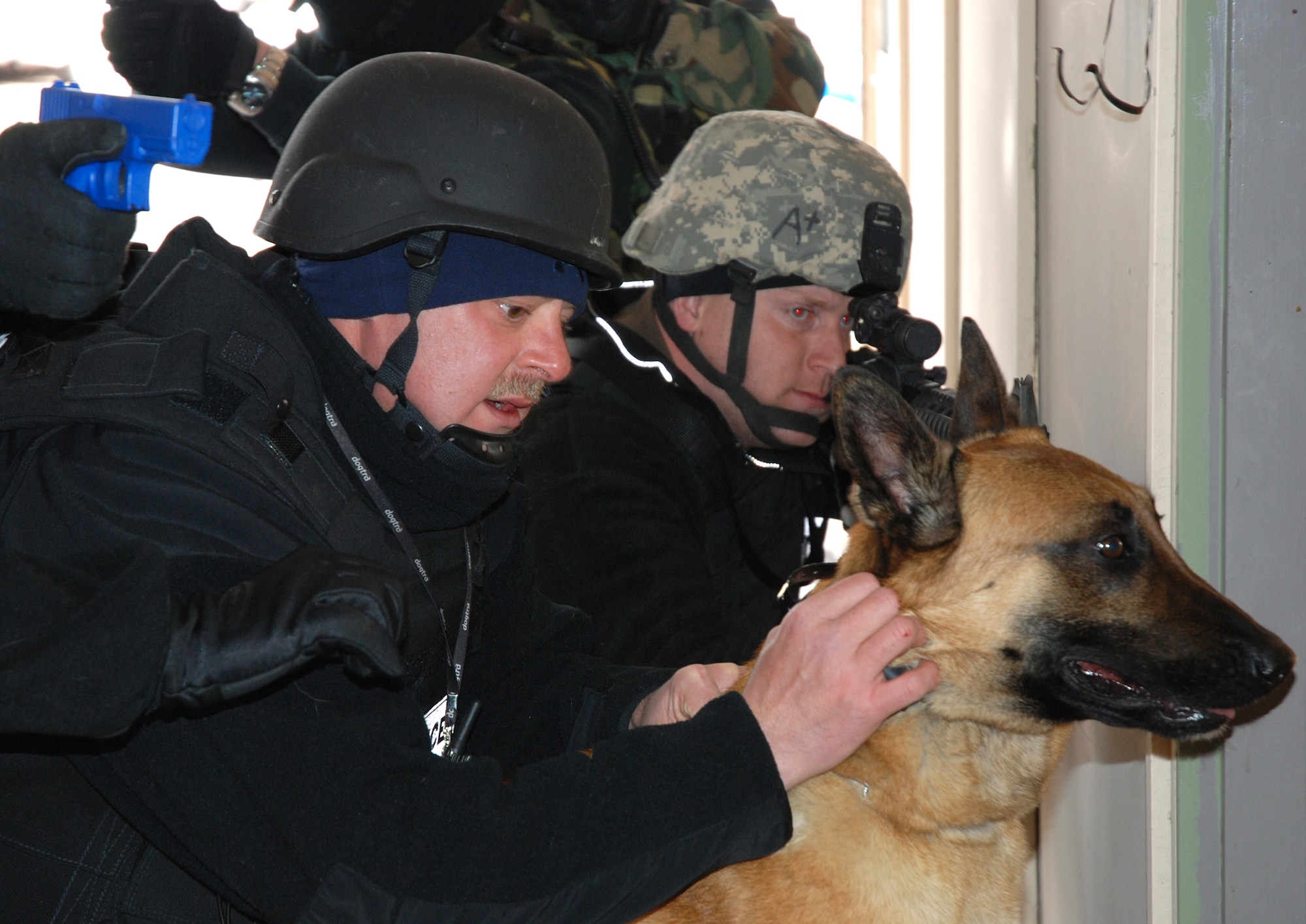 A civilian canine handler, his dog and a forced-entry team prepare to enter a simulated suspect’s house April 11 in the U.S. Air Force Academy base housing complex. Several civilian and military law enforcement agencies around the Colorado Springs area participated in canine Special Weapons and Tactics, or ‘SWAT’ training to better understand the use of dogs during a tactical engagement with criminal or unfriendly forces. (U.S. Air Force photo/Senior Airman Stephen Collier)