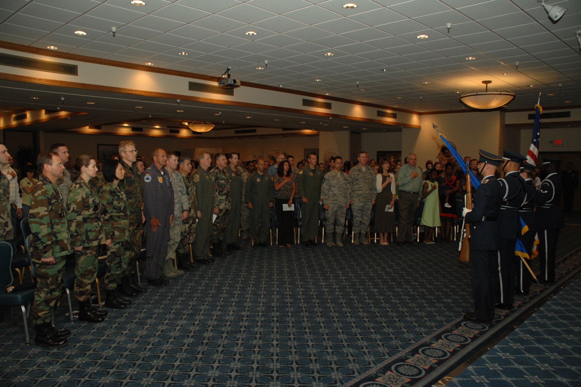 HOLLOMAN AIR FORCE BASE, N.M.-- Members of Team Holloman rise during the singing of the national anthem during a squadron merger ceremony in the Desert Sands Enlisted Club ballroom here April 4. The ceremony combined the 49th Services Squadron and 49th Mission Support Squadron into the 49th Force Support Squadron.