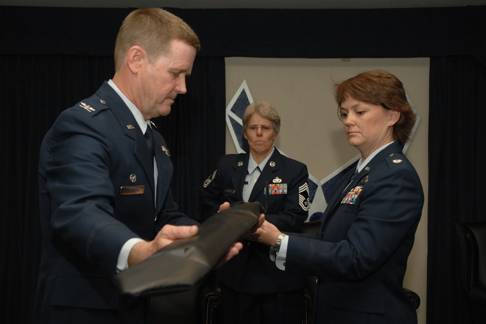 HOLLOMAN AIR FORCE BASE, N.M. -- Lt. Col. Kristin McCoy, 49th Force Support Squadron commander, cases the 49th Services Squadron guidon during a ceremony here April 4. Assisting her is Col. Mark Engeman, 49th Mission Support Group commander, and Chief Master Sgt. Vyanne Roush, 49 FSS superintendent.