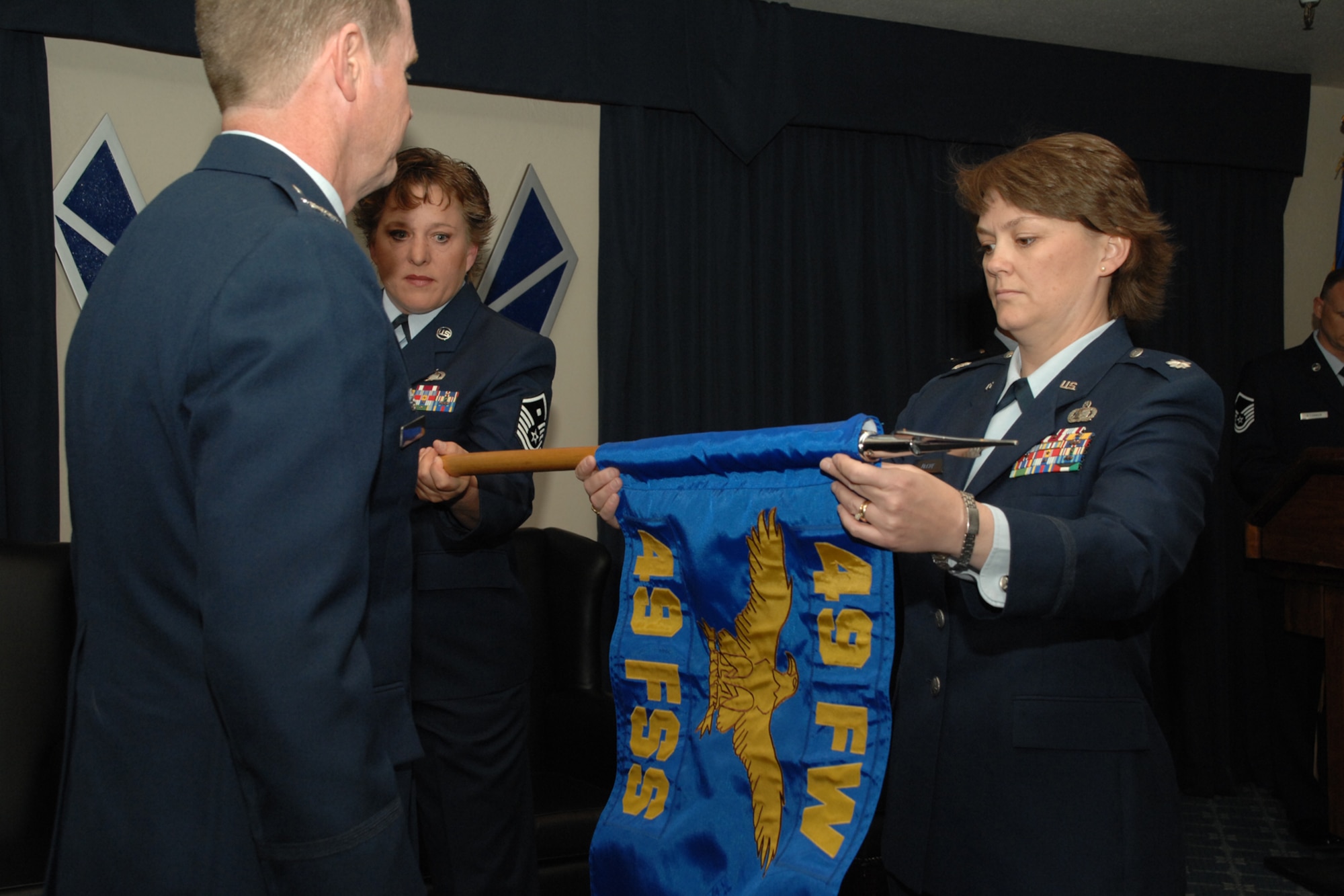 HOLLOMAN AIR FORCE BASE, N.M. -- Lt. Col. Kristin McCoy, 49th Force Support Squadron commander, unveils the squadron guidon during a ceremony here April 4. Assisting her is Col. Mark Engeman, 49th Mission Support Group commander, and Master Sgt. Kimberly Marshall, 49 FSS first sergeant.