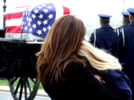 Family members of former missing in action Airman, Maj. Robert F. Woods, watch as the cason carrying him is prepared to move to a grave site April 9, 2008, at Arlington National Cemetery, Va. On Nov. 30, 2007, the Air Force announced that Major Woods, along with co-pilot Capt. Johnnie C. Cornelius, were identified and their remains returned to the United States from Vietnam. On June 26, 1968, Major Woods and Captain Cornelius were flying a visual reconaissance mission over Quang Binh Province, Vietnam, when their O-2A Skymaster aircraft crashed in a remote mountainous area. Major Woods was buried with full military honors nearly 40 years after he disappeared in the crash. (U.S. Air Force Photo/Master Sgt. Scott T. Sturkol)