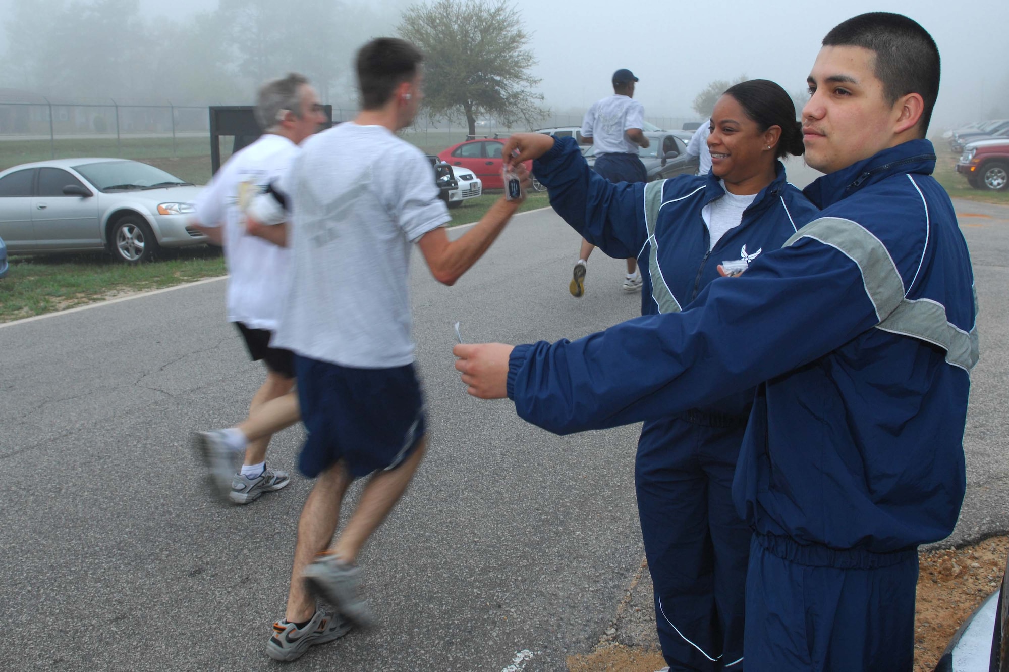 SHAW AIR FORCE BASE, S.C. -- First Lt. Katherine Andrade and Airman 1st Class Francisco Mejia, 20th Medical Operations Squadron, hand out dog tags that have the phone numbers for Airman Against Drunk Driving and Sexual Assault Response Coordinator during a warrior run April 11. In fall of 2005, the SARC instituted the Unit Victim Advocate Program, which educates volunteers through many hours of training to help the sexual assault victims. (U.S. Air Force photo/Senior Airman William Coleman.)