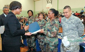 Mariylnn M. Bland, vice-chair, Princes Georges County Council, presents Airman 1st Class Ava Epps, 316th Contracting Squadron, as well as other Andrews members a proclamation commemrating their volunteerism at Benjamin D. Foulois Elementary School, Morningside, Md., during half-time baskeball game on April 4. The members are volunteer mentors and tutors at the school near Andrews. (US Air Force/Bobby Jones)