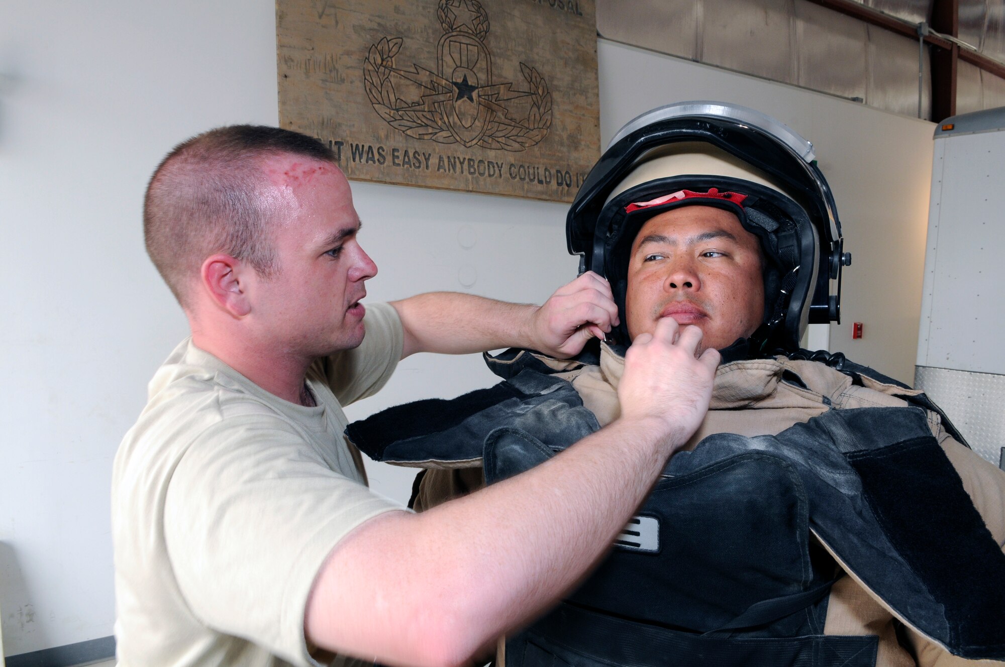 Senior Airman Seth Hall, 379th Expeditionary Civil Engineer Squadron explosive ordnance disposal, helps Tech Sgt.  William Cameron, another EOD technician, put on a bomb suit at a Southwest Asia air base April 10. EOD members need assistance putting on suits because of the restricted movement and weight of the suit. They are first responders whenever there is a major base incident or if there is an improvised explosive device in the CENTCOM area of responsibility. Airman Hall is deployed from Barksdale Air Force Base, La. and Sergeant Cameron is deployed from Nellis Air Force Base, Nev. (U.S. Air Force photo/Tech. Sgt. Johnny L. Saldivar)
