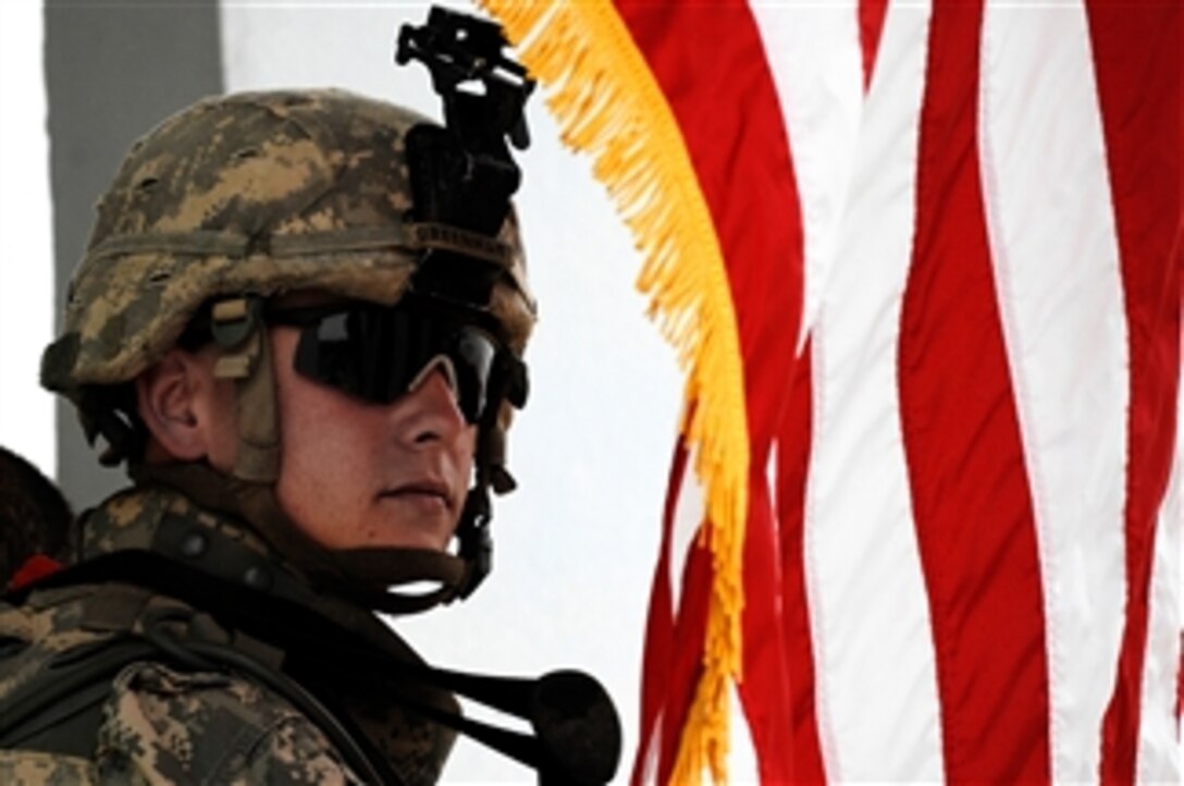 A U.S. Army soldier assigned to the 10th Mountain Division's 2nd Battalion, 22nd Infantry Regiment, stands at parade rest next to an American flag during the oath of 2,000 Sons of Iraq members in Kirkuk, Iraq, April 7, 2008. 