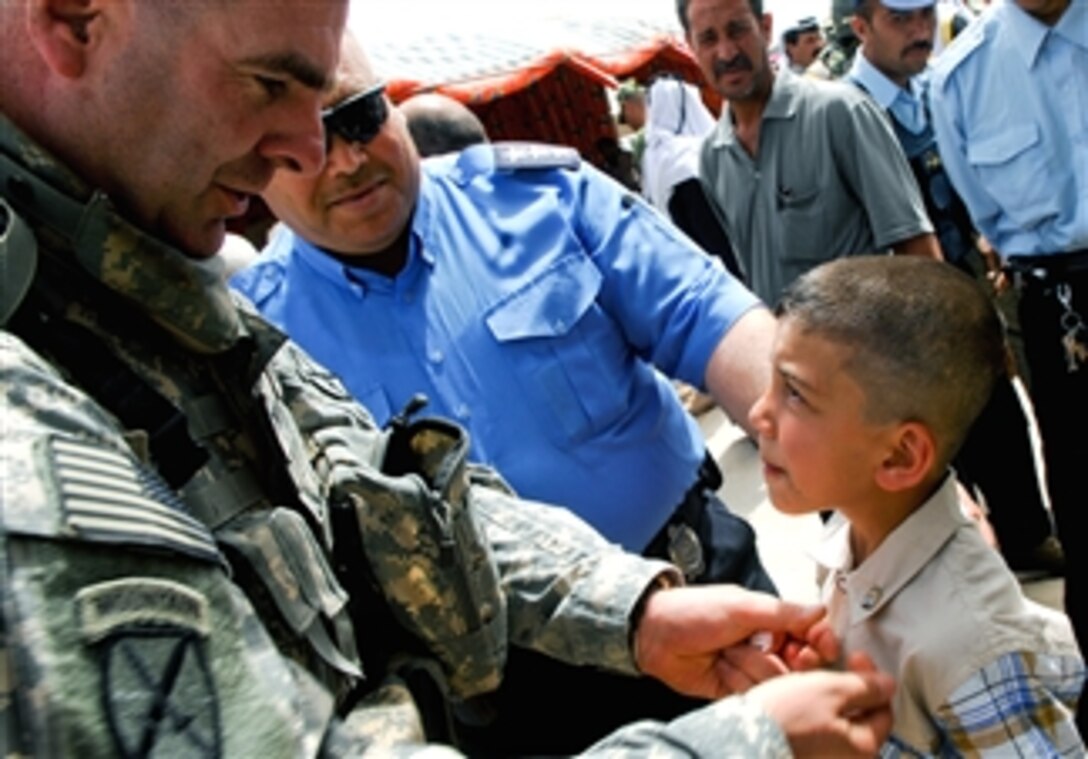 U.S. Army Col. David Paschal, commander, 10th Mountain Division's 1st Brigade Combat Team, pins a unit crest onto a little boy and also on Sons of Iraqi police chief Maj. Gen. Jalmal Tahir after signing a contract to employ 2,000 Sons of Iraq members in Kirkuk, Iraq, April 7, 2008. 