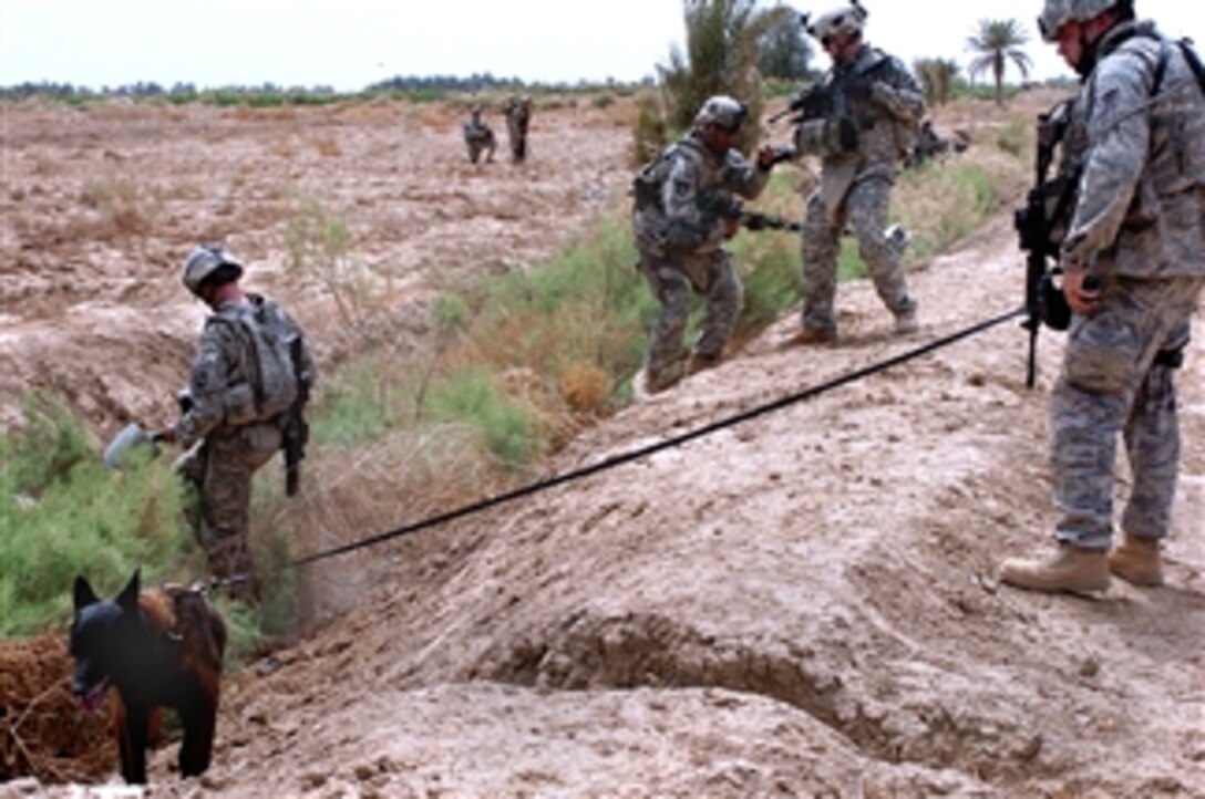 U. S. Air Force Staff Sgt. Matthew Elgen and his military working dog Bram check a canal for munitions during Operation Dalian near Diyarah, Iraq, April 7, 2008. 