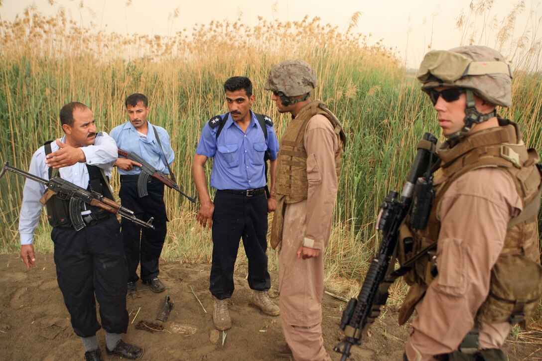 Sgt. Michael J. Anderson, a squad leader with Company F, 2nd Battalion, 24th Marine Regiment, talks to the Iraqi police responsible for locating a weapons cache the Marines set out to check April 11. The IPs said that this was the possible location of an anti-aircraft weapon earlier in the war and was disabled by coalition fire. It is these tips given by the Iraqi Police and Iraqi Army that are helping the Marines cripple the enemy without firing a weapon.