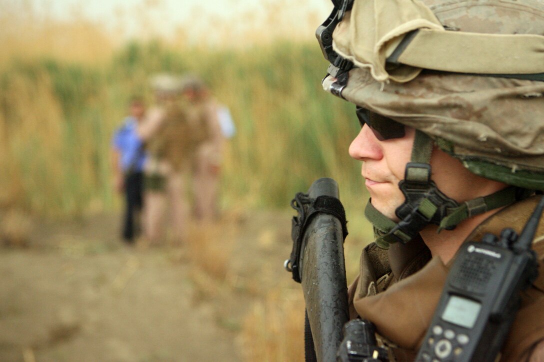 Cpl. Aaron J. Rogers, a team leader with Company F, 2nd Battalion, 24th Marine Regiment, provides security while his squad leader speaks with the Iraqi Police at the sight of a possible weapons cache April 11. The Iraqi Police and Iraqi people regularly tip off the Marines on the locations of weapons caches in hope to earn the Marines' trust and provide a better life for their family.
