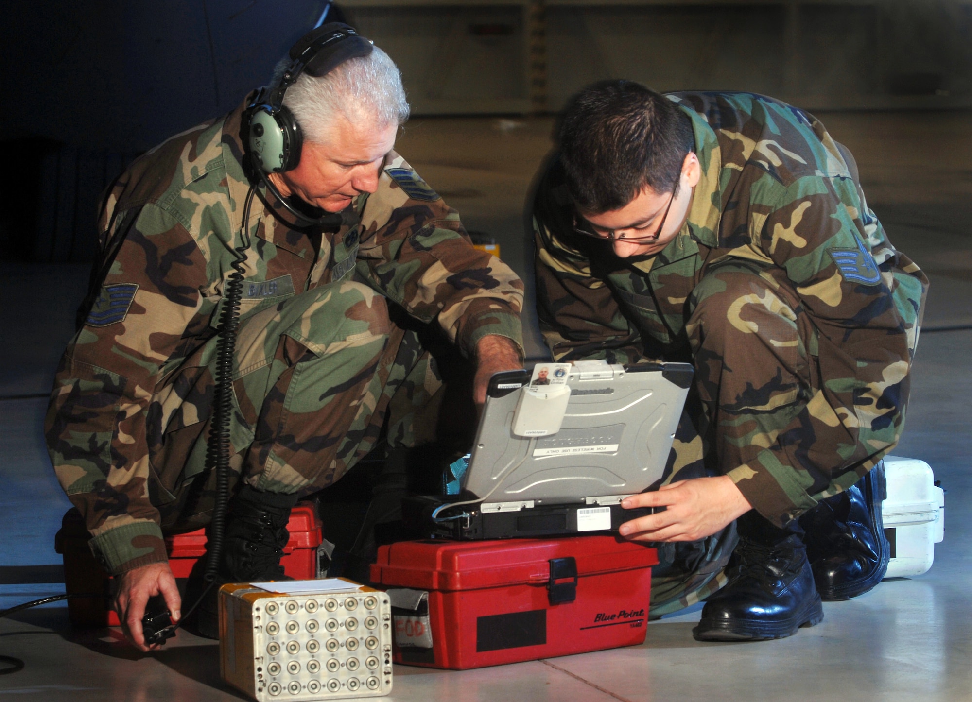 Technical Sgt. Paul Bixler (left) and Staff Sgt. John Gray, both electronic warfare technicians, from the 452nd Maintenance Squadron, March Air Reserve Base, reference their Digital Tecnical Order System (D-TOS) while installing a test set on the flare bucket of a C-17 Globemaster III cargo aircraft. (Photo by Val Gempis)
