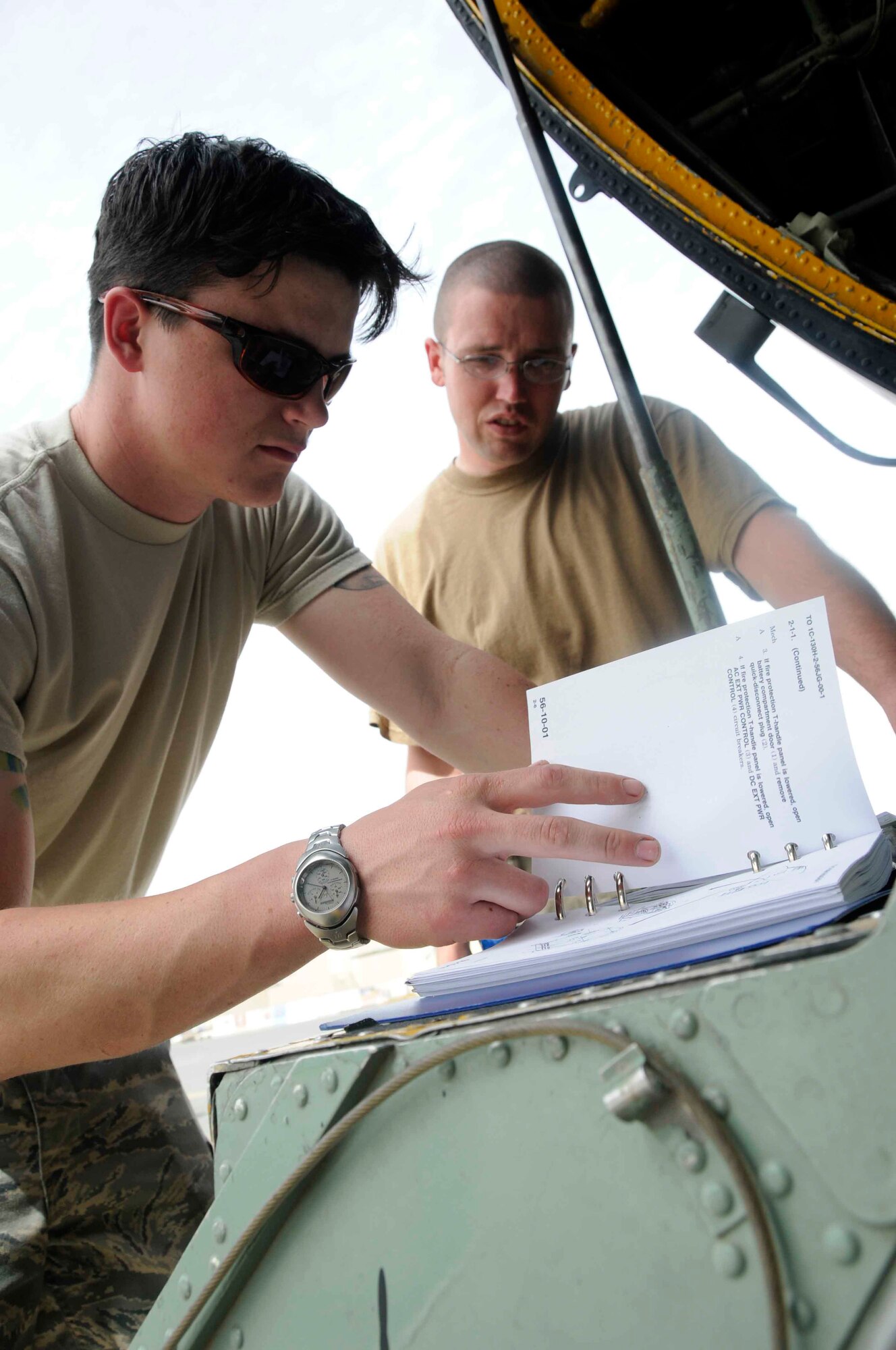 SOUTHWEST ASIA -- Senior Airman Richard Herling and Tech. Sgt. Kevin Sanderson, 746th Expeditionary Aircraft Maintenance Unit C-130 crew chiefs from Pope Air Force Base, N.C., go through a job guide to ensure all preparations are completed to remove and replace a window on "Patches," the 746th Expeditionary Airlift Squadron’s newly-acquired C-130E, tail number 62-1817. (U.S.Air Force photo/ Senior Airman Domonique Simmons.)