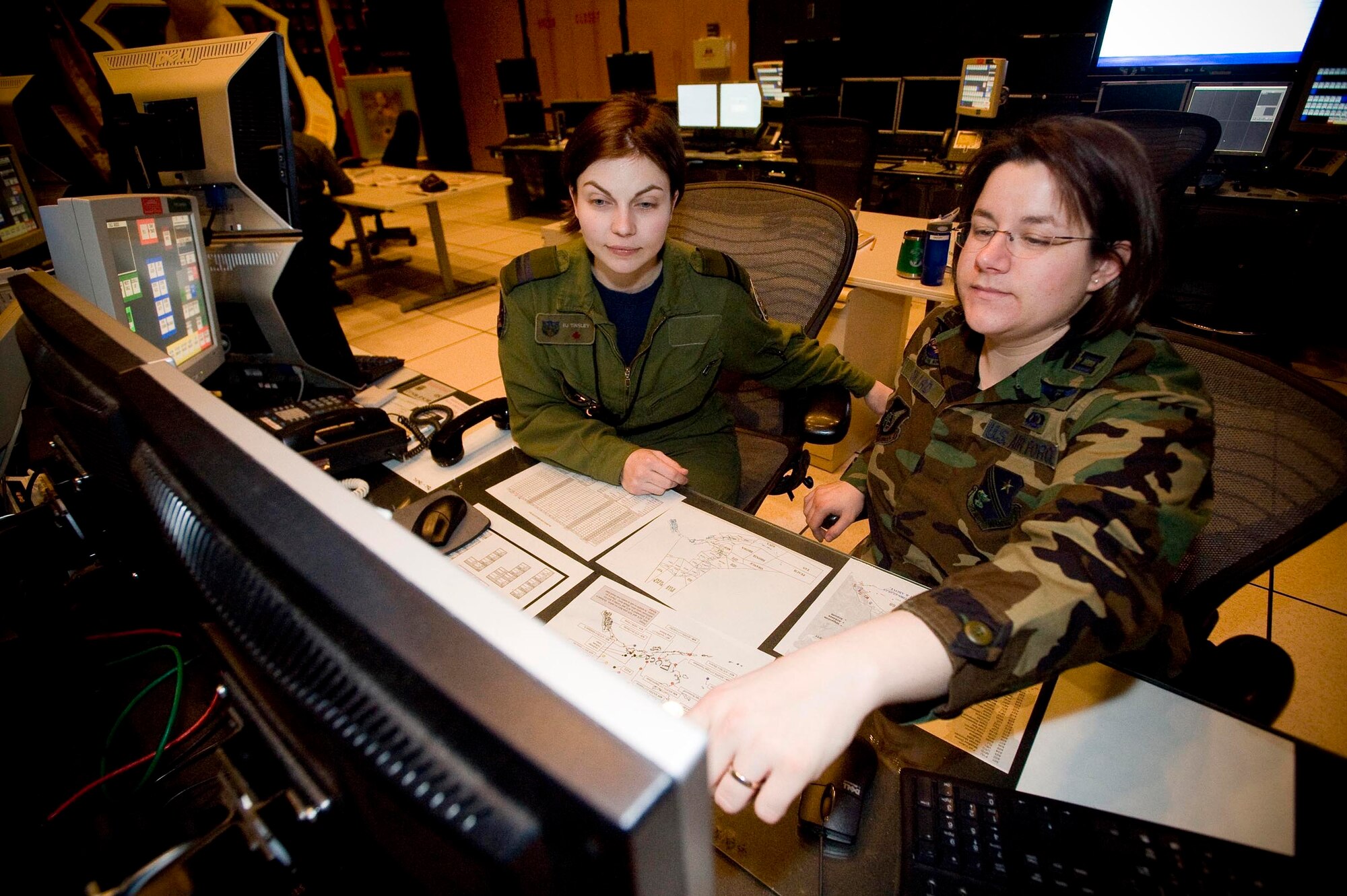 ELMENDORF AIR FORCE BASE ALASKA -- Canada Air Force Capt. B.J. Tinsley, 176th Air Control Squadron, and Air Force Capt. Carrie Howard, 176th ACS review tactics for intercepting potentially hostile aircraft. The 176th Air Control Squadron is part of Alaskan North American Aerospace Defense Command (NORAD) Region whose mission is to protect Alaska air sovereignty. (U.S. Air Force photo by Airman 1st Class Jonathan Steffen) 