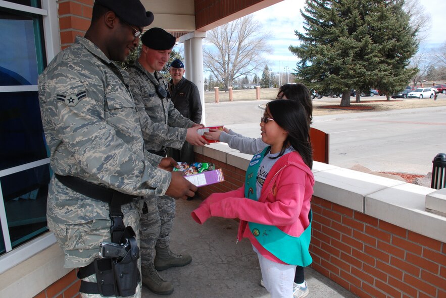 Leah Siapno (right) and Mackenzie Nolan hand donated Girl Scout cookies to gate guards Airman 1st Class Darryl King and Airman 1st Class Matthew Brinks, both of 90th Security Forces Squadron, Sunday. The girls were from Girl Scout Troop 160 out of Fort Collins whose troop designated Warren as their “Gift of Caring.” The troop collected 120 donated boxes of Girl Scout cookies for the base (U.S. Air Force photo/2nd Lt. Lisa Meiman).