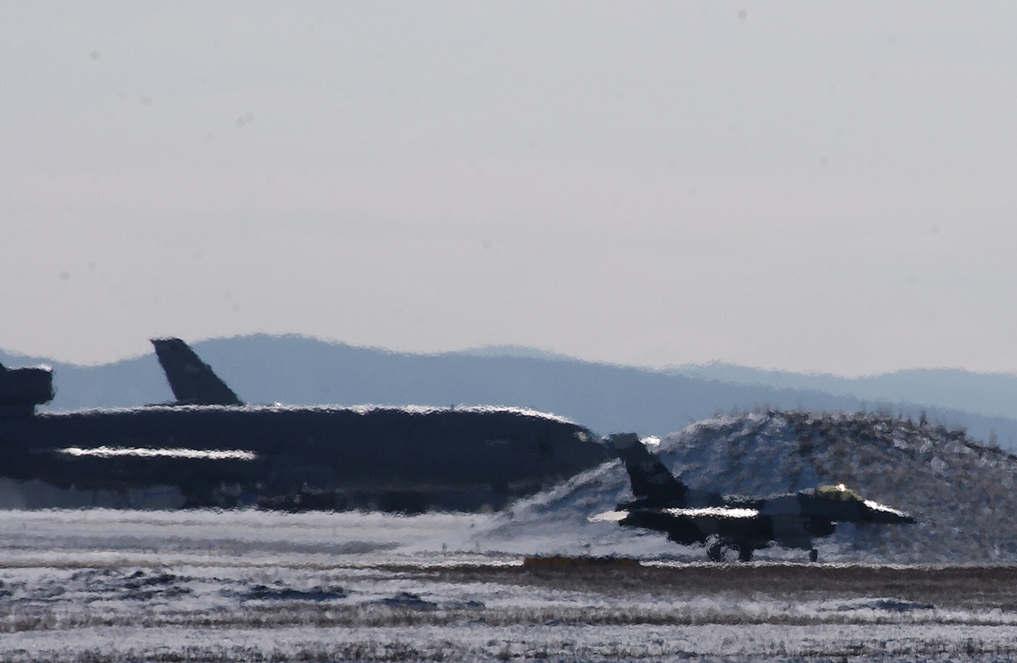 A F-16 Aggressor waits behind the exhaust from another F-16 Fighting Falcon as it taxies by at Eielson Air Force Base, Alaska April 11, 2008. RED FLAG-Alaska 08-2 is a Pacific Air Forces command directed field training exercise which provides joint offensive counter-air, interdiction, close air support and large force employment training in a simulated combat environment. (U.S. Air Force Photo/Airman 1st Class Jonathan Snyder)