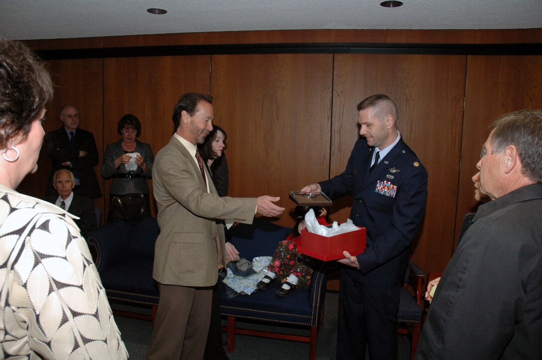 Maj. Phil Heseltine presents a prisoner of war/missing in action bracelet he wore for 18 years to the Chuck Woods, son of Maj. Robert F. Woods, whose name is on the bracelet, during the funeral for Major Woods April 9 at Arlington National Cemetery in Virginia. Mr. Woods then presented the bracelet to his own son. Major Heseltine is the executive officer for the Air Force Expeditionary Center commander at Fort Dix, N.J. (U.S. Air Force photo/Tech. Sgt. Scott T. Sturkol) 