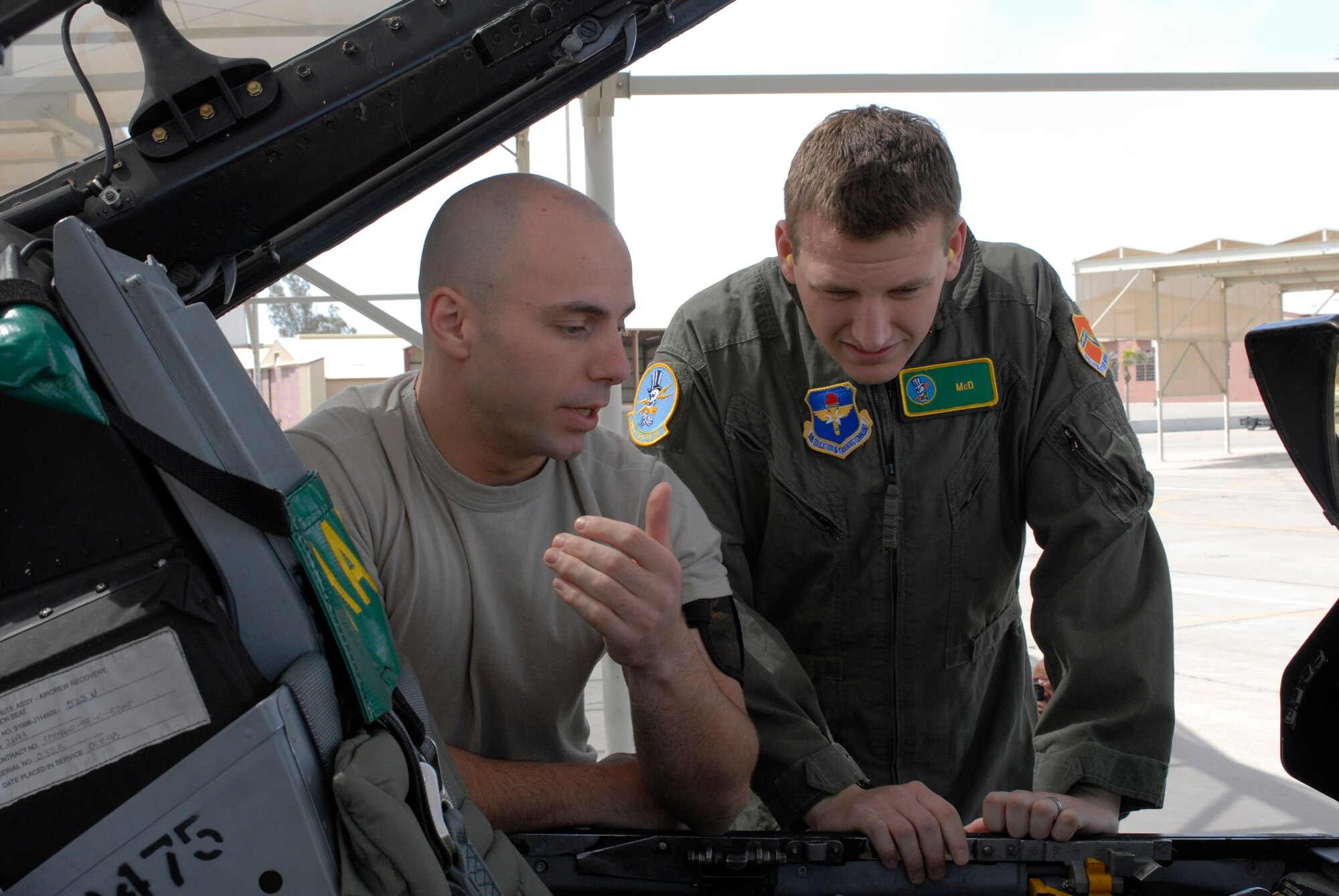 Senior Airman Mason Bergeron, a 56th Operations Support Squadron aircrew flight equipment continuation training instructor, explains the proper way to egress an aircraft to NASCAR driver Michael McDowell. Luke members met and got signed photos of Mr. McDowell before his orientation flight in an F-16. (U.S. Air Force photo/Staff Sergeant Christopher Hummel)