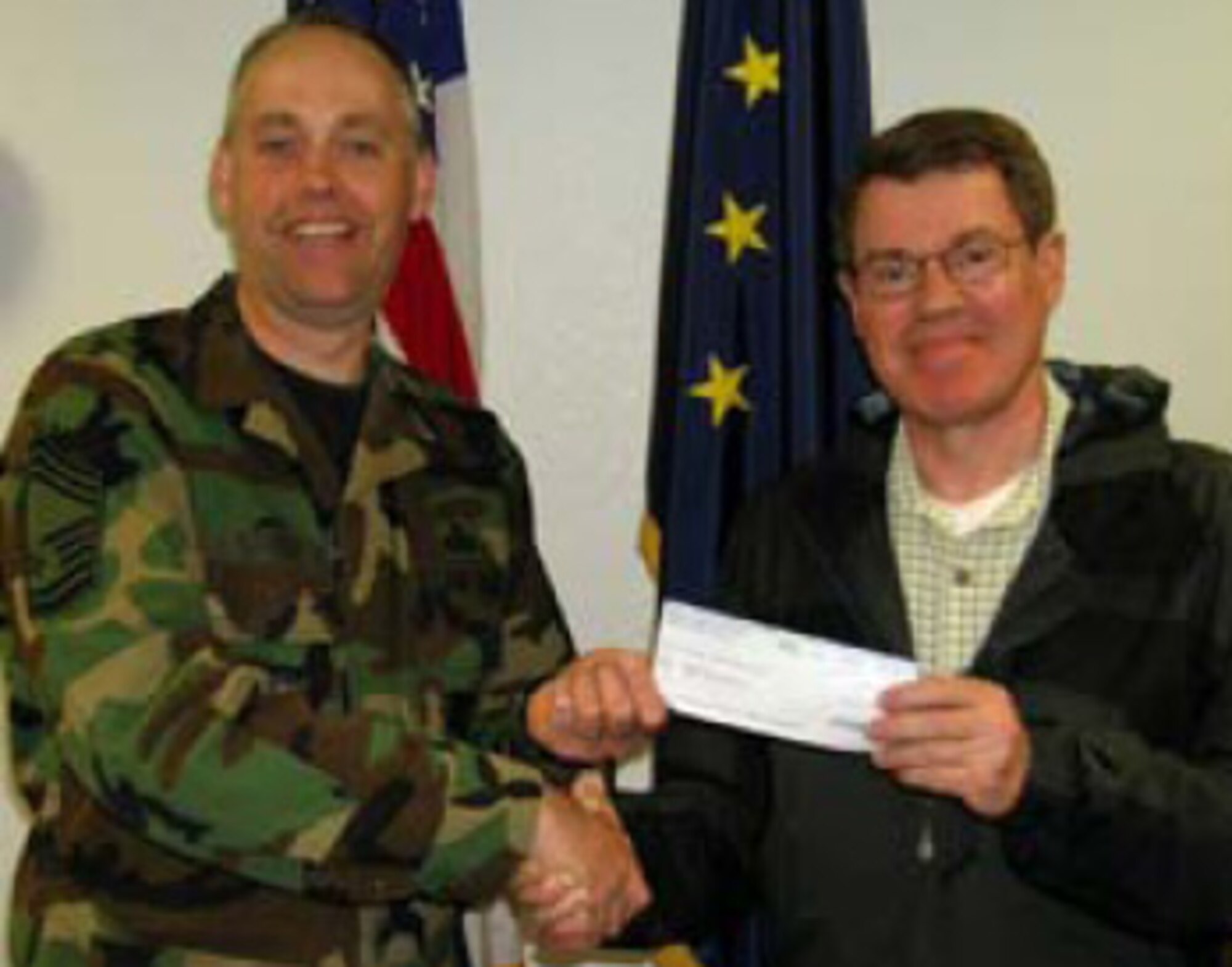 Alaska USA’s Military Operations Branch Manager, Carl Bradford, shown here presenting CMSgt. David Streit a $500 check in support of this year’s Family Day. Photo by SSgt. Eric Hamilton, 176 WG/PA.