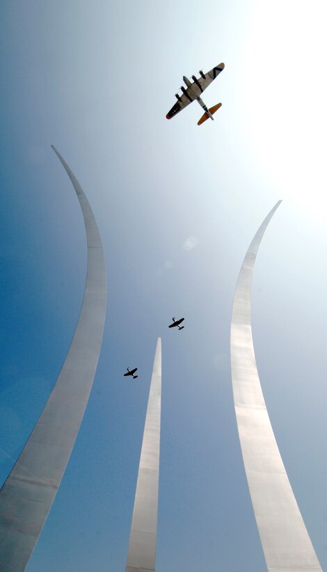 A B-17 Flying Fortress (top of frame), a P-40 Kittyhawk and a P-51 Mustang soar over the spires of the Air Force Memorial April 10 in Arlington, Va. The three World War II-era planes flew over a ceremony honoring the 30,000 American Airmen who gave their lives flying from British bases during World War II. The event was arranged by the American Air Museum at Duxford, England, which is celebrating its 10th anniversary. The first Americans to serve in England were based at Duxford in 1918. During World War II it was also home to the 78th Fighter Group from 1943 to 1945. Former British Prime Minister John Major served as guest of honor for the ceremony. (U.S. Air Force photo/Andy Morataya)