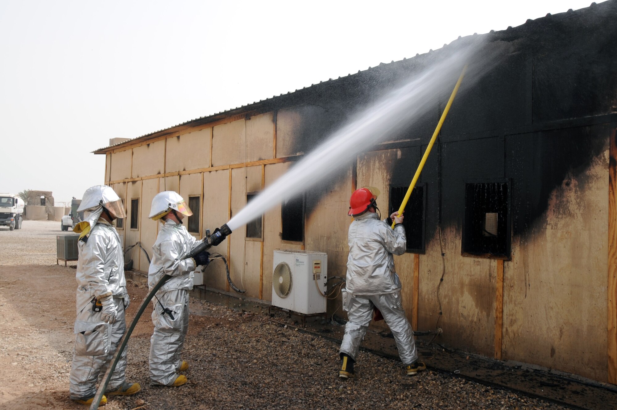 ALI BASE, Iraq -- The 407th Expeditionary Civil Engineering Squadron fire fighters extinguish spot fires on a building in the Romanian camp here April 11.  The Air force emergency response forces respond to all emergencies here including coalition partners, such as the Romanians, or other services, like the U.S. Army and Navy. (U. S. Air Force photo / Tech. Sgt. Sabrina Johnson)