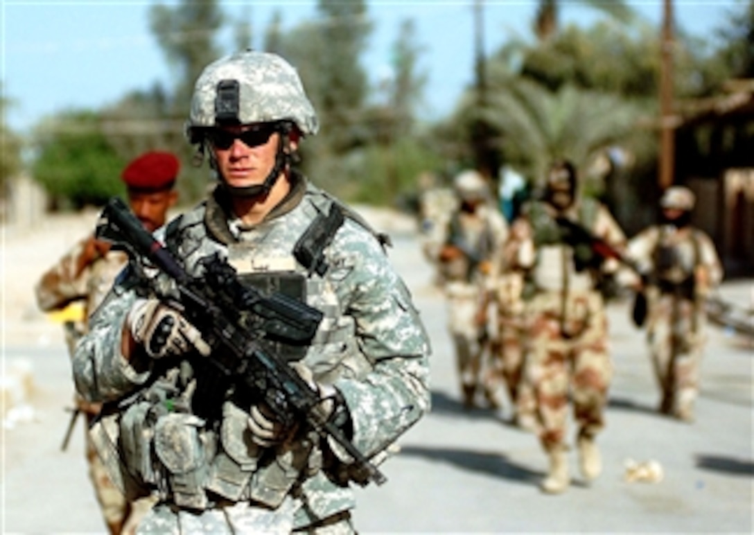 U.S. Army Staff Sgt. Charles Moore, a psychological operations sergeant the 101st Airborne Division's 3rd Brigade Combat Team, leads Iraqi soldiers through the town of Al Rashid during operations, April 1, 2008.