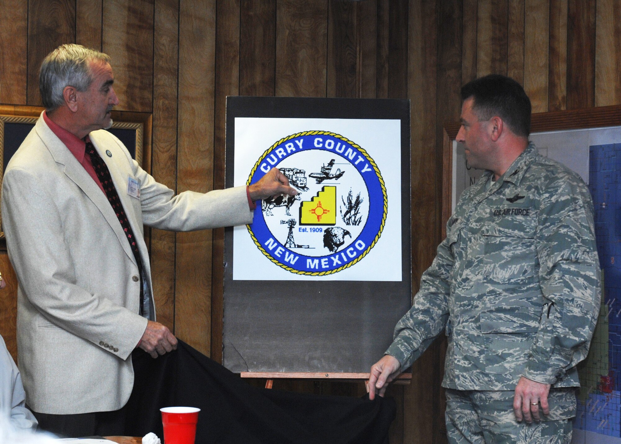 CANNON AIR FORCE BASE, N.M. - -  J. Albin Smith, Curry County, commisioner and chairman,  District 4, and  Col. Timothy Leahy, 27th Special Operations Wing commander, unveil the new Curry County logo April 15.  The unveiling took place at the Curry County Courthouse. (U.S. Air Force photo by Airman 1st Class Evelyn Chavez)