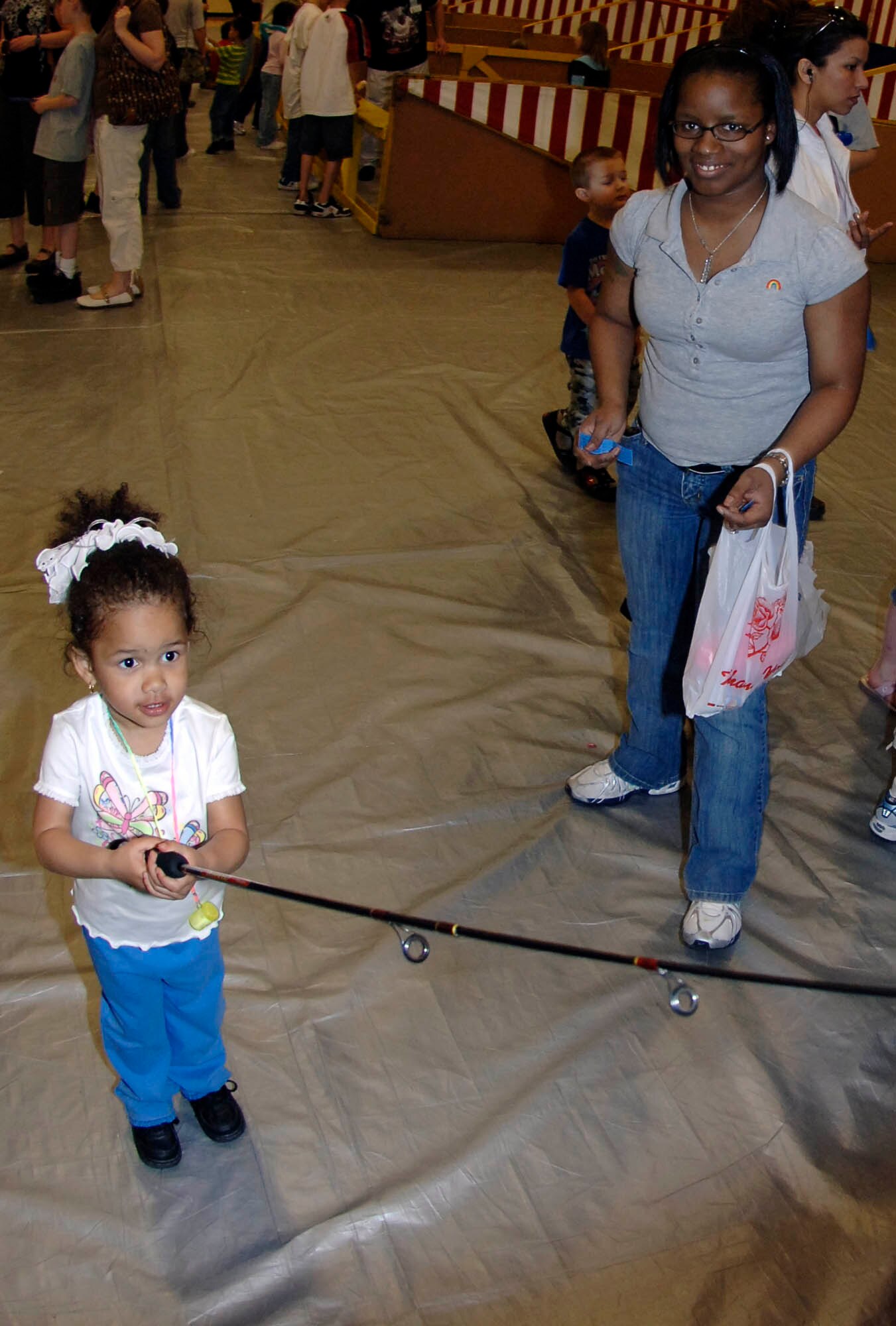 FAIRCHILD AIR FORCE BASE, Wash. – Trinity Ballew casts a fishing line as her mother, Airman 1st Class Rodshell Ballew, 92nd Medical Group pharmacy technician, looks on. This was one of many games at the carnival at Michael Anderson Elementary school sponsored by the Parent Teacher Organization. The event took place on April 12 to support and raise money for the school. (U.S. Air Force photo/Staff Sgt. JT May III)