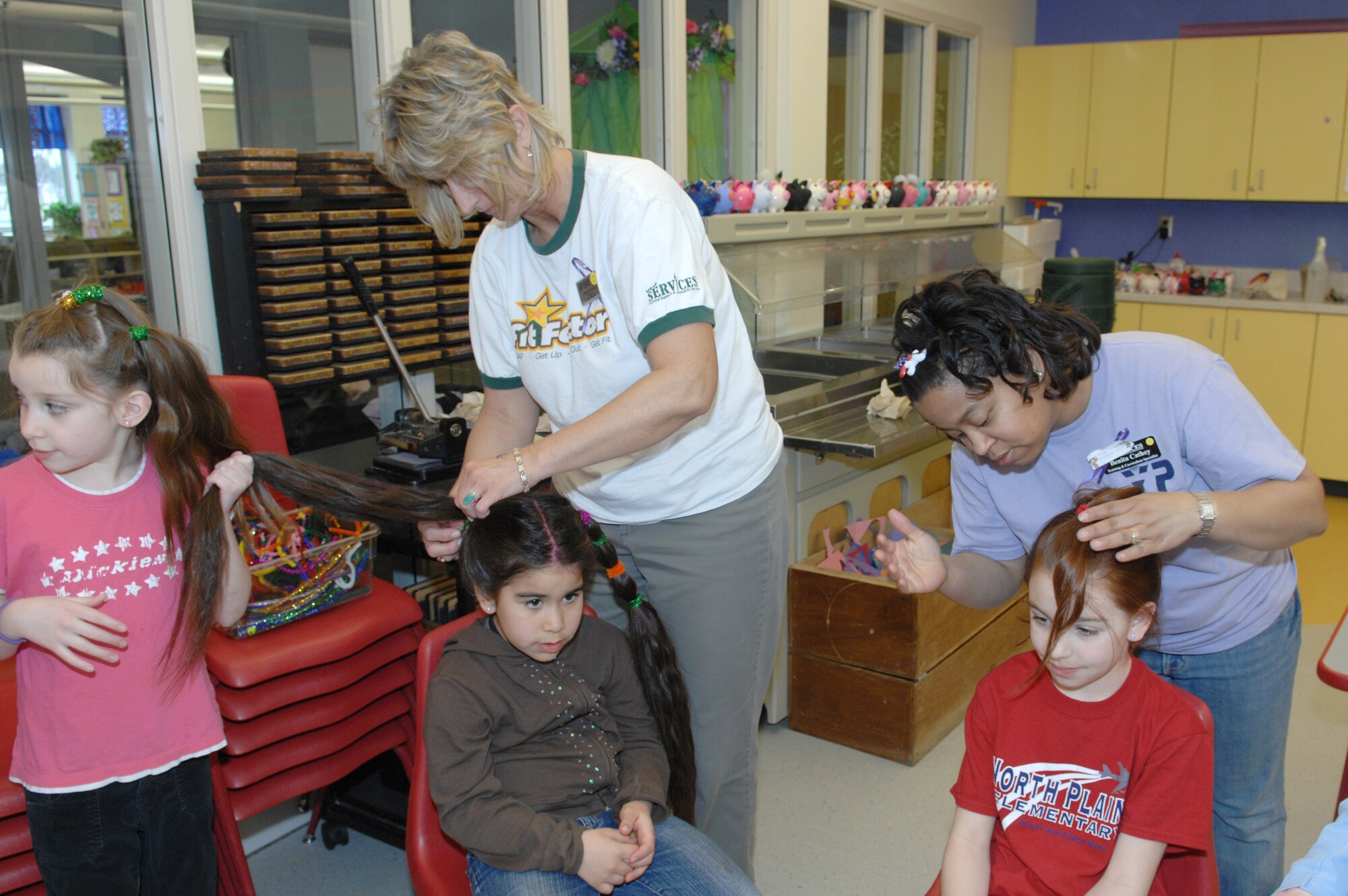 MINOT AIR FORCE BASE, N.D.—  Katie Hayes, daughter of Tech. Sgt. James Hayes, 5th Bomb Wing chapel staff, helps Ronda Knutson, director of youth programs, straighten out Chelsey Stark’s hair as part of "Wacky Hair Day," a Month of the Military Child event. Chelsey is the daughter of Senior Master Sgt. Jeffery Stark, 5th Operations Support Squadron. Also, Benita Cathey, training and curriculum specialist, straightens out Jessica Fischer’s hair. Jessica is the daughter of Master Sgt. Michael Fischer, 5th Civil Engineer Squadron. The Youth Center, as well as many other organizations on base, have activities and events planned during the month of April. (U.S. Air Force photo by Senior Airman Cassandra Jones)