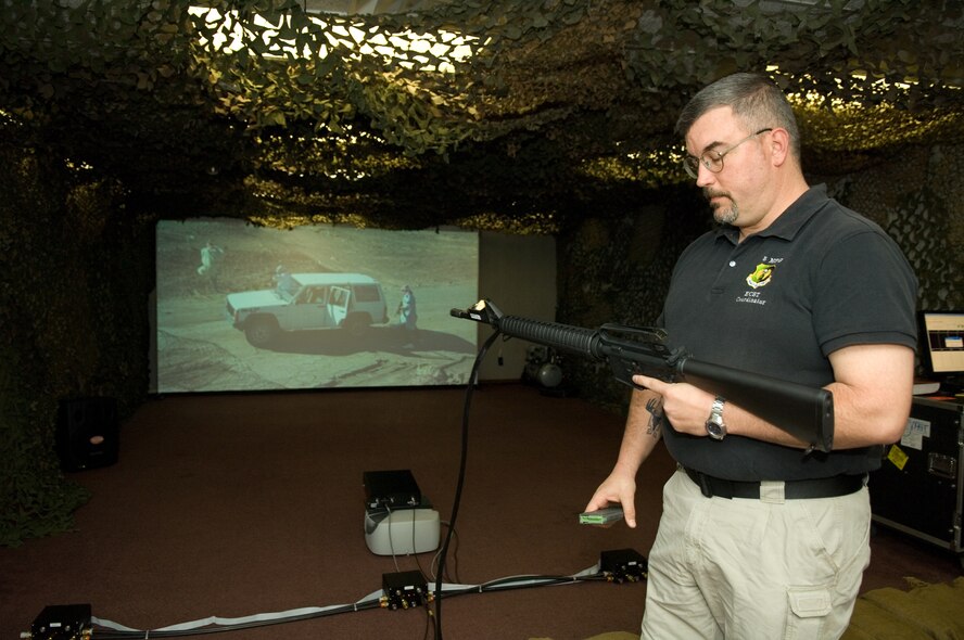 MINOT AIR FORCE BASE, N.D. -- Rodney Onstott, base combat skills trainer, performs a weapons check before preparing to engage the enemy on an Engagement Systems Trainer 2000 here April 14. The trainer is part of expeditionary combat skills training all Airmen must attend before deploying to Iraq or Afghanistan. (U.S. Air Force photo by Airman 1st Class Jesse Lopez)  